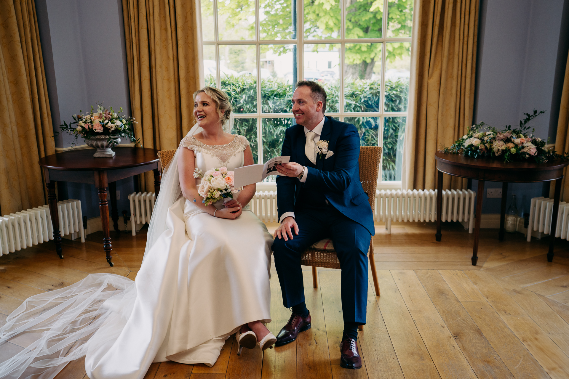 A bride and groom sitting on a chair in a room