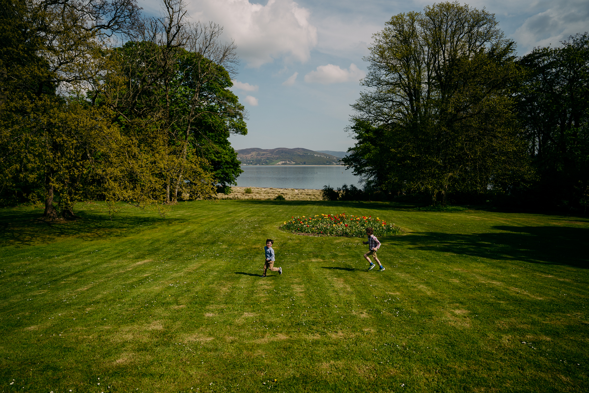 A group of people walking on a grassy field by a body of water