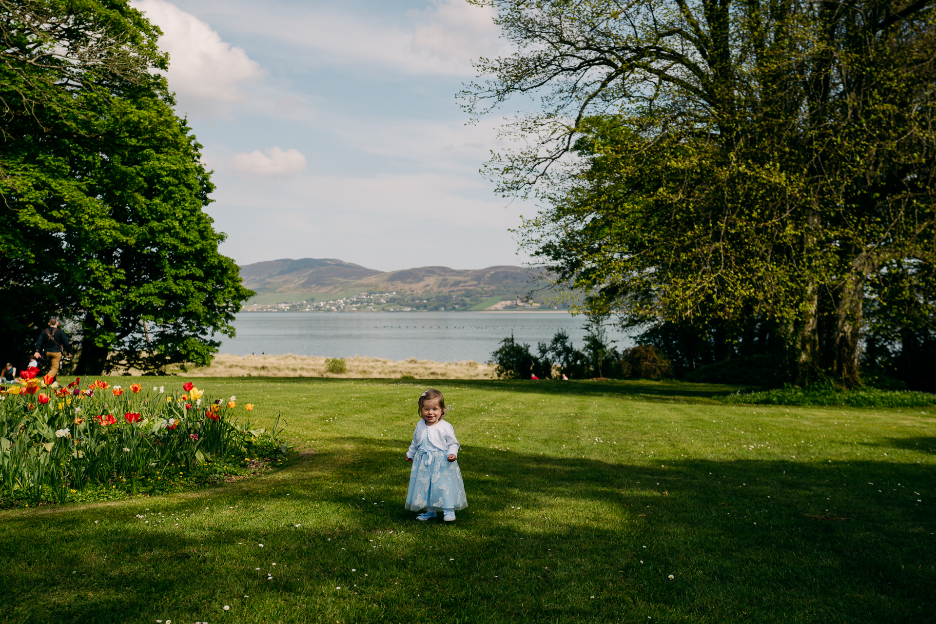 A child standing in a grassy area next to a body of water