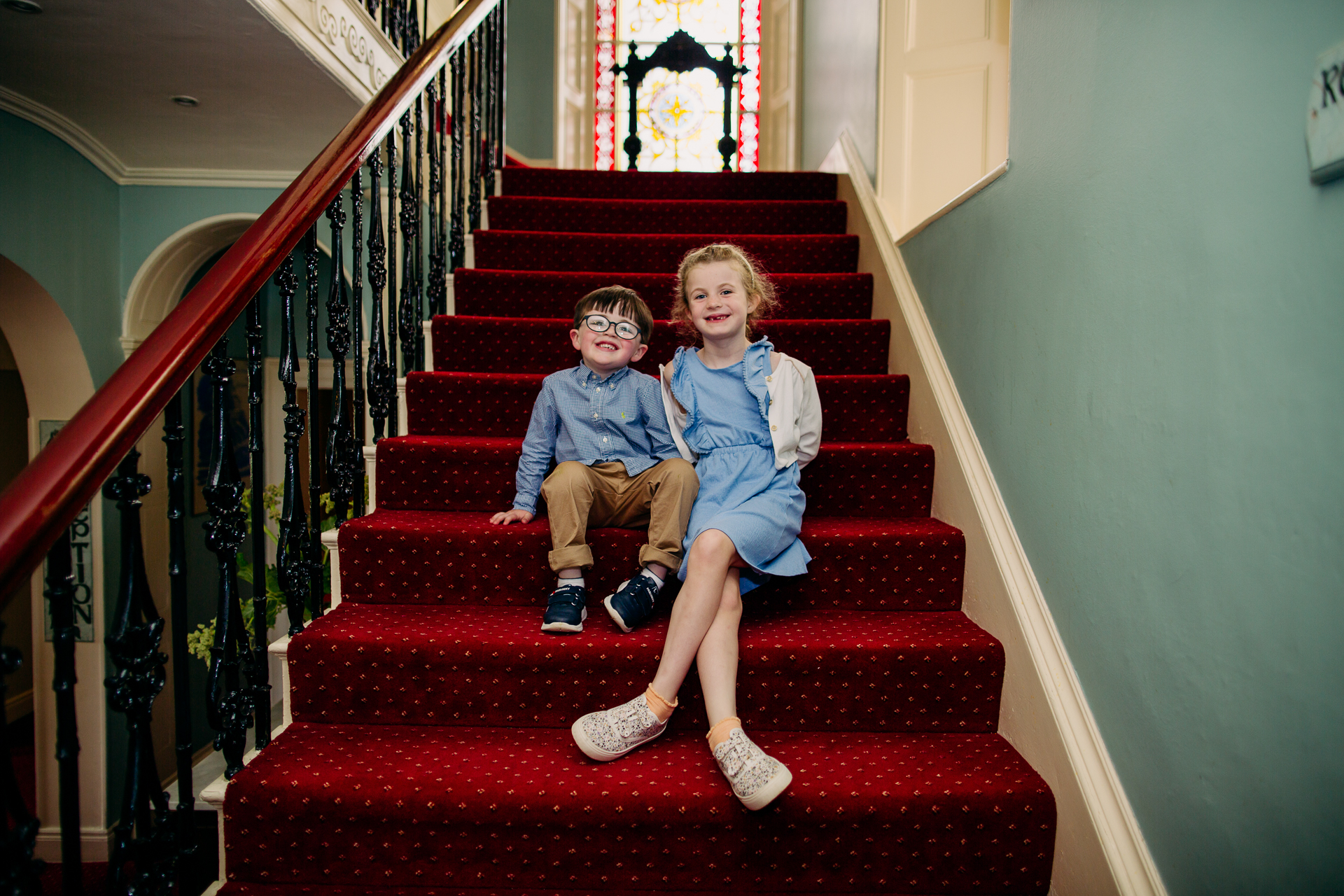 A boy and girl sitting on a red staircase