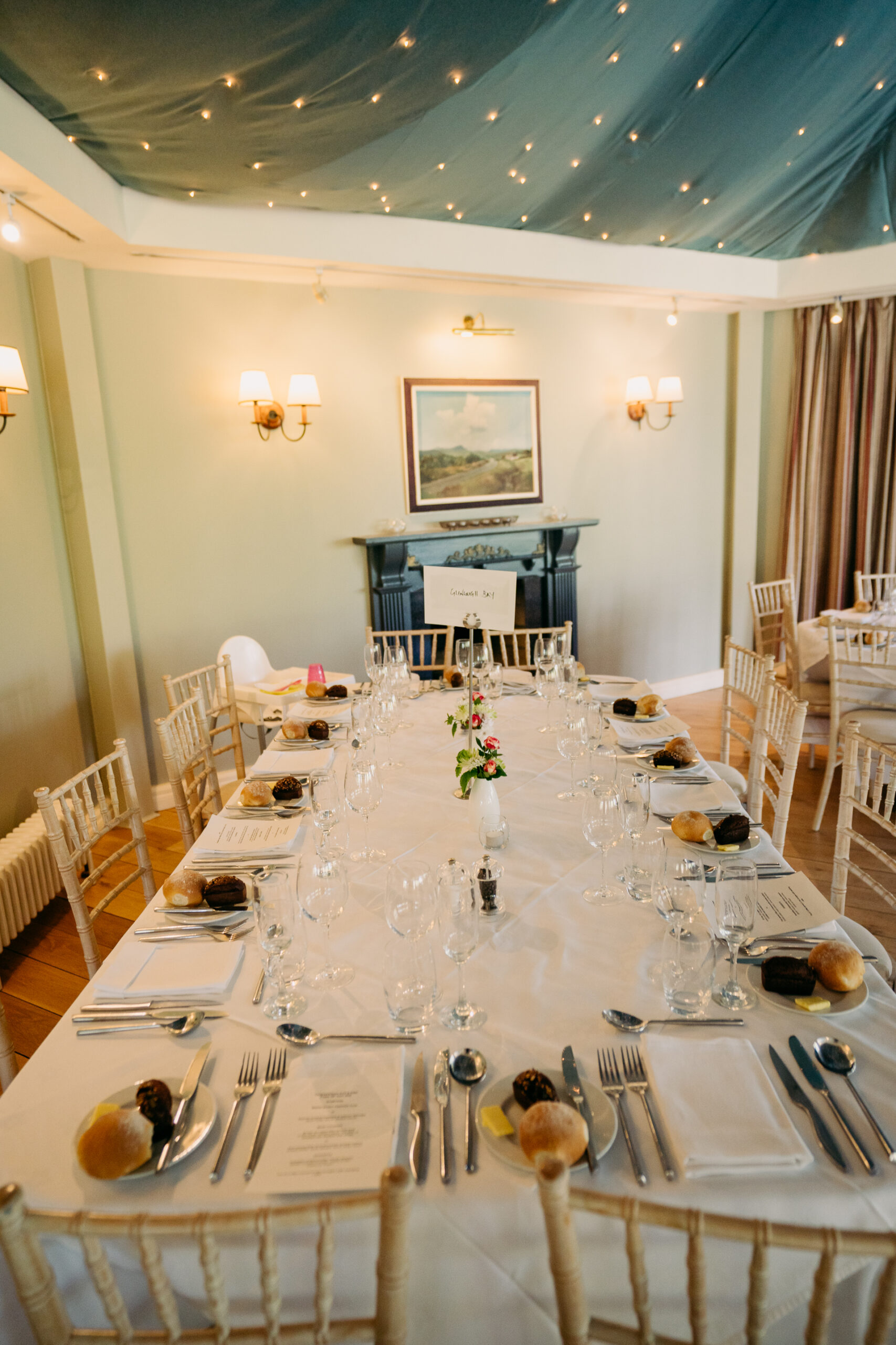 A dining room table with white cloths and silverware