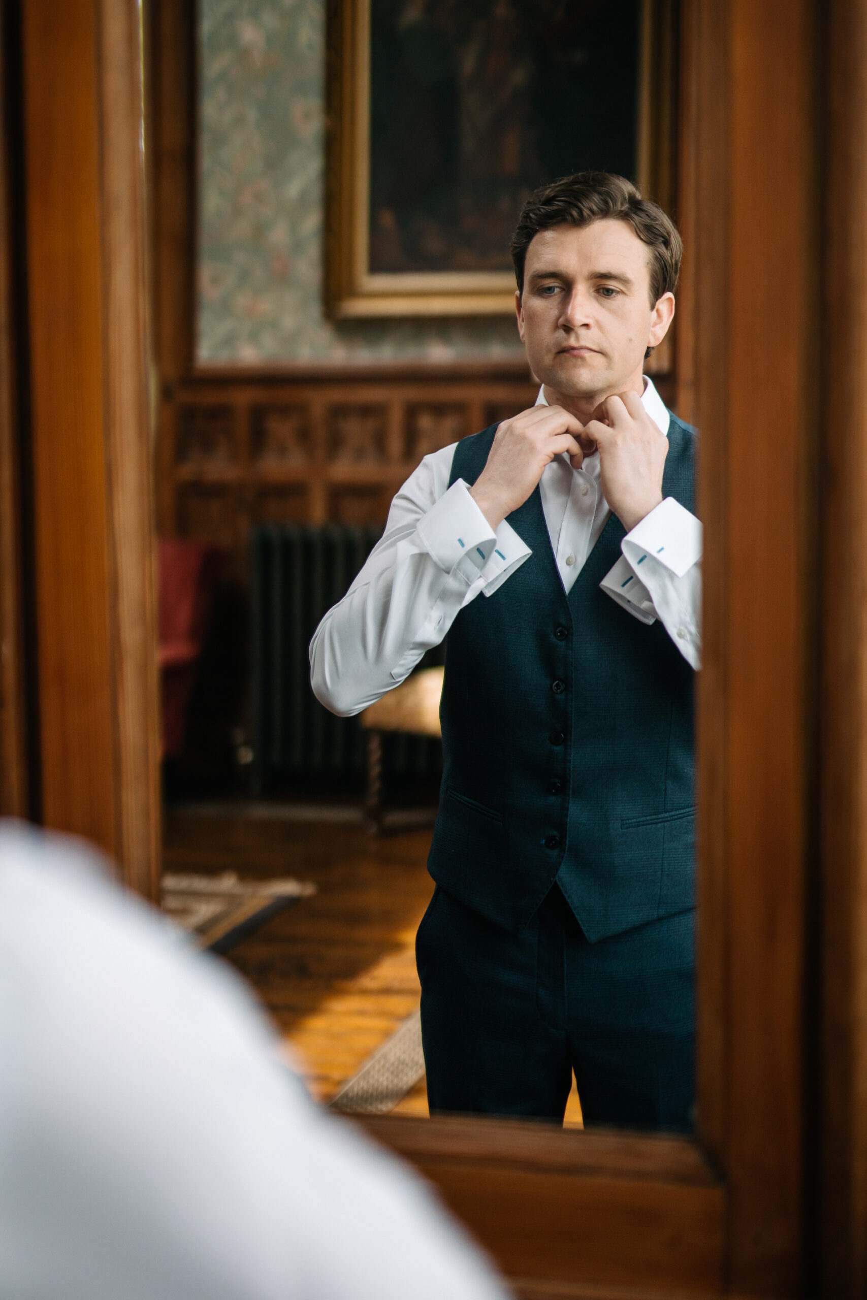 A person in a suit adjusting the tie