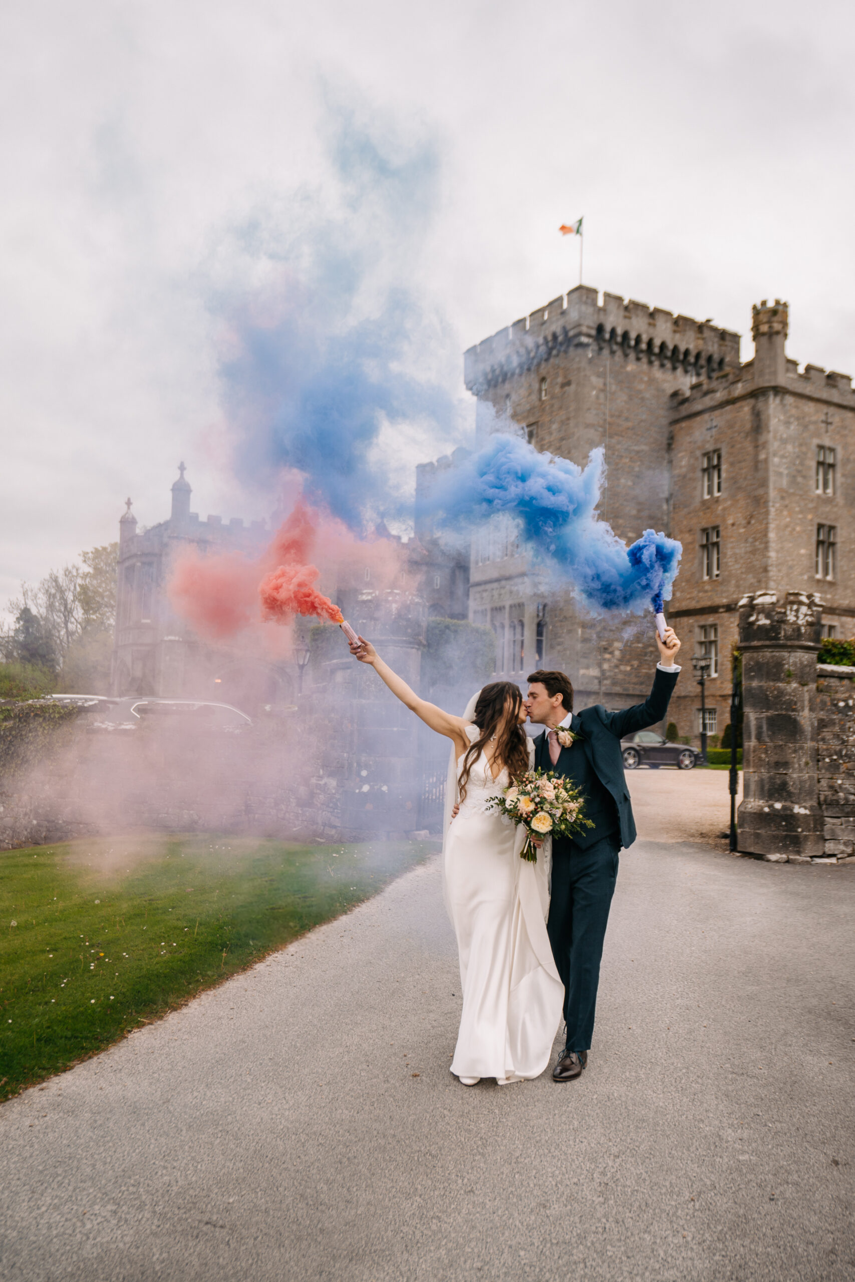 A man and woman holding hands and posing for a picture with a castle in the background