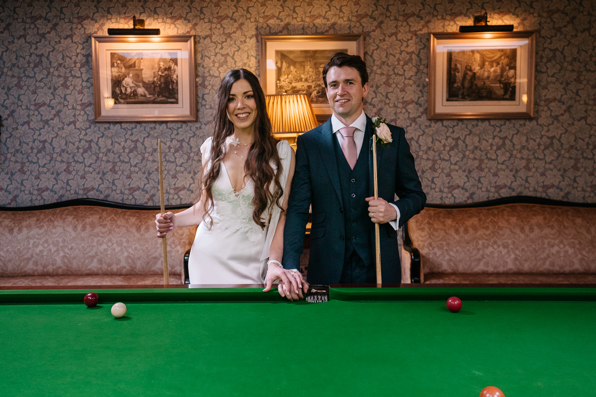 Bride and groom posing elegantly by the billiard table in Markree Castle's game room.