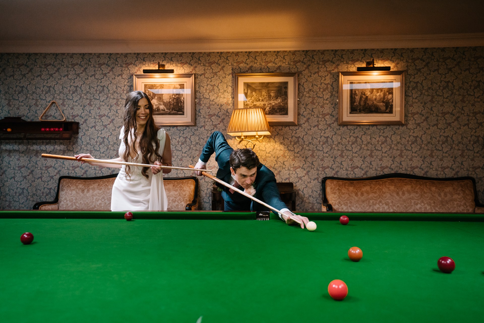 Bride and groom posing elegantly by the billiard table in Markree Castle's game room.