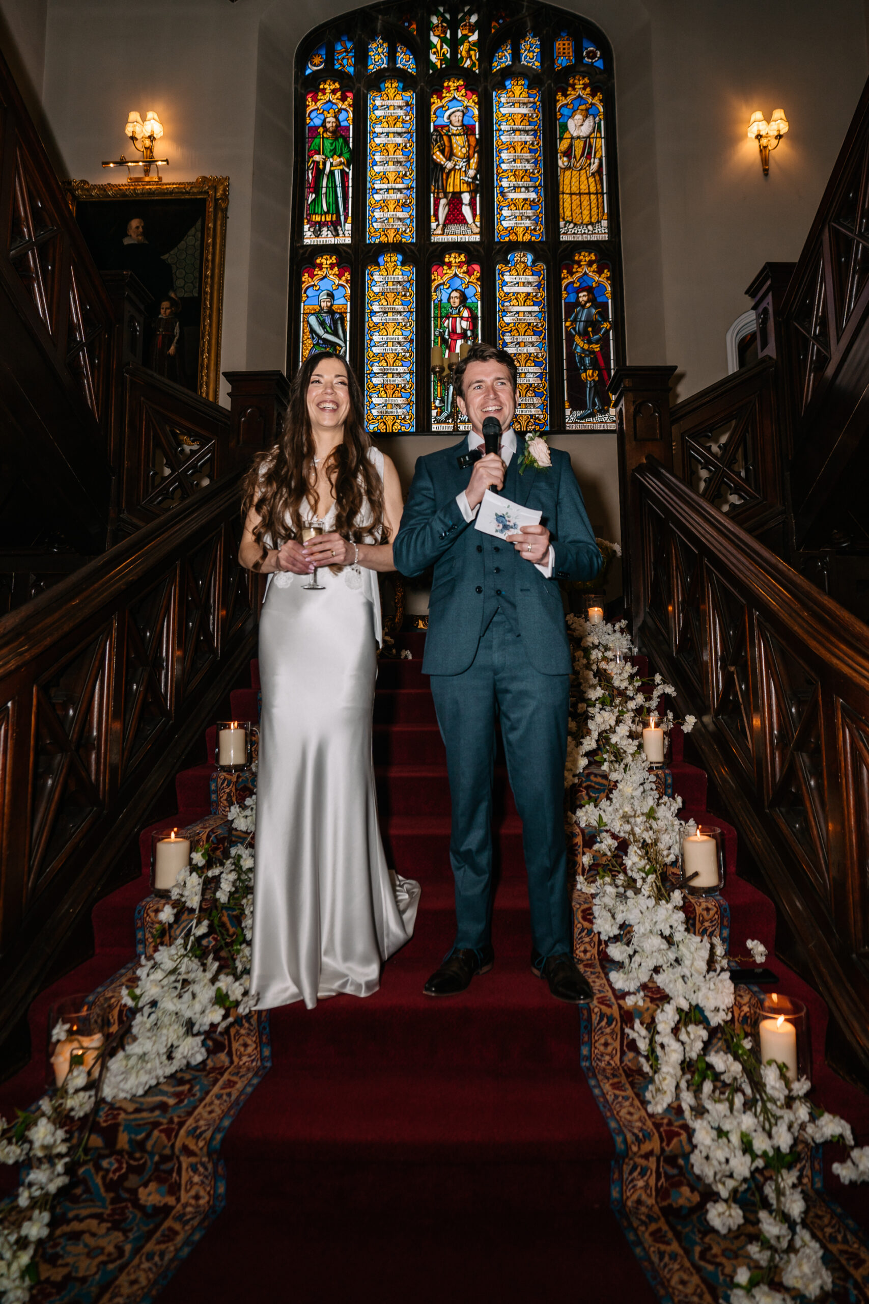 A man and woman posing for a picture in front of a stained glass window