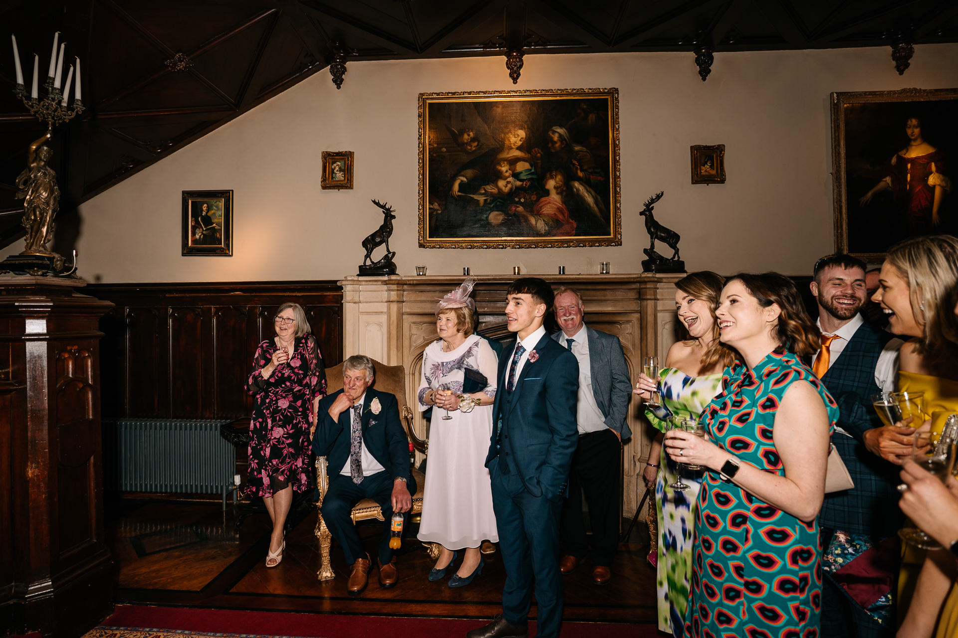 A group of people standing in a room with a painting on the wall