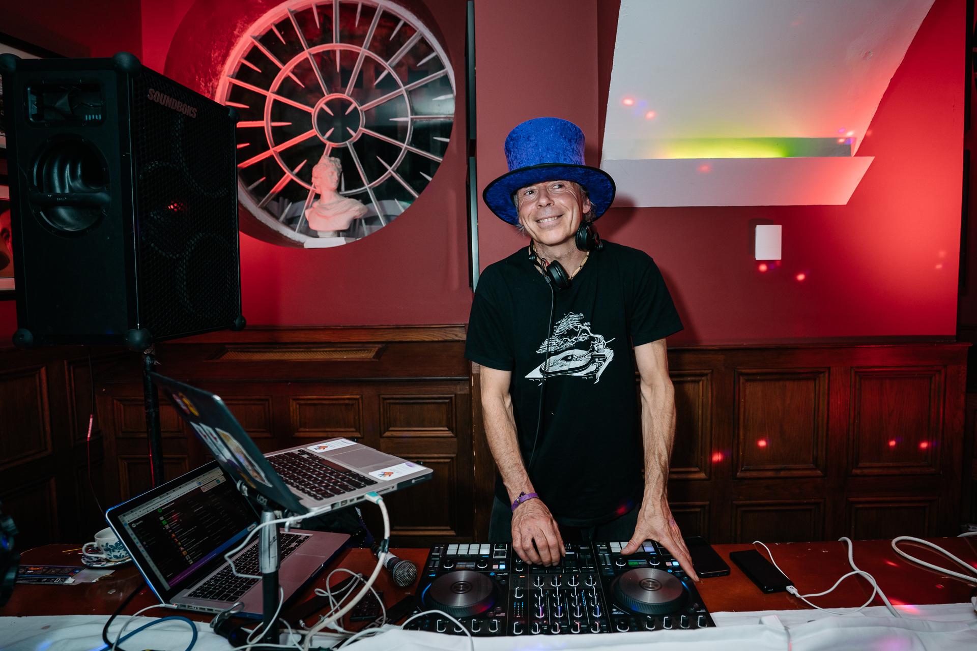 A man wearing a hat and standing in front of a dj booth