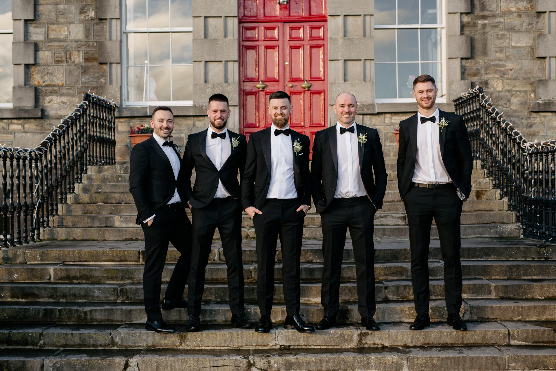 A group of men in tuxedos standing on stairs