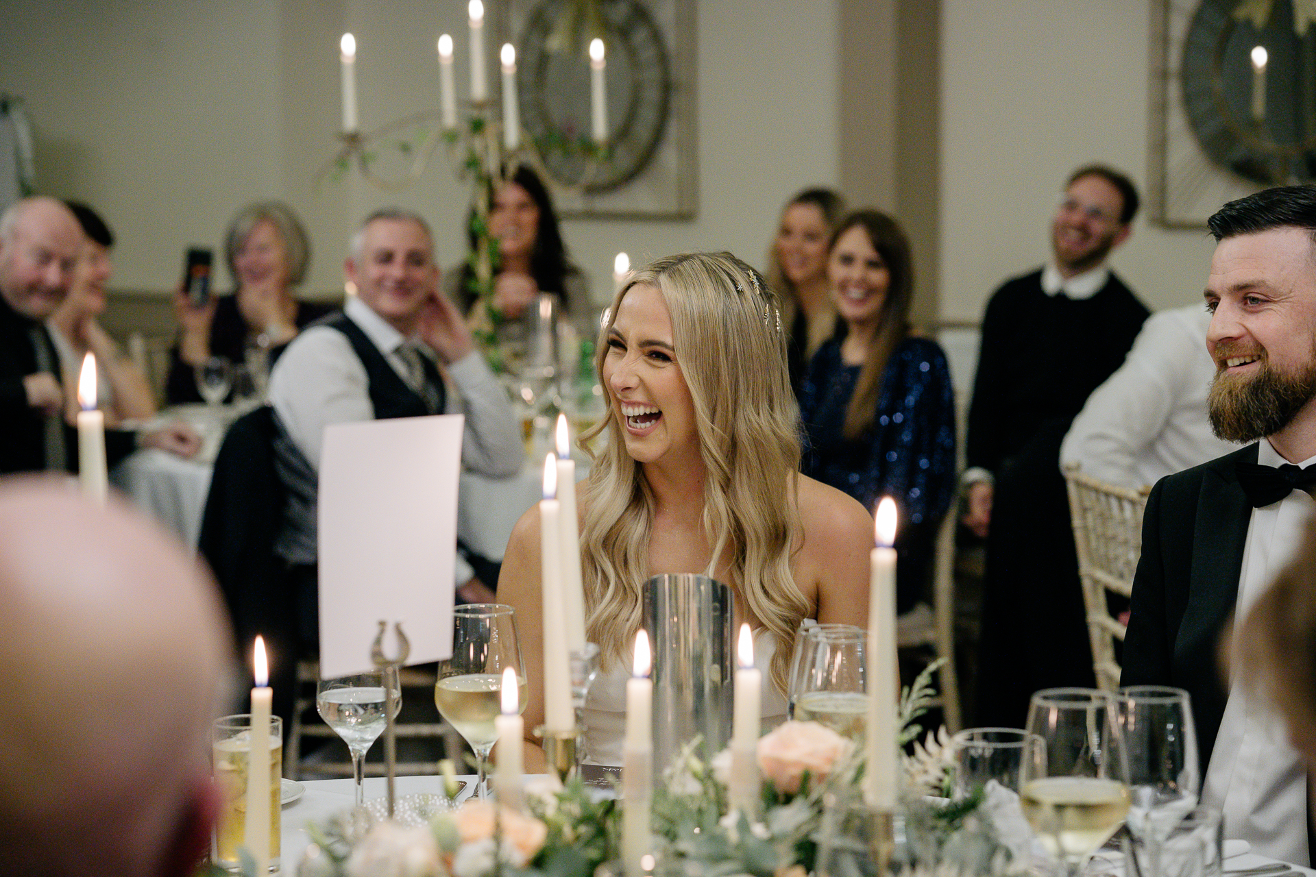 A group of people sitting at a table with candles and flowers