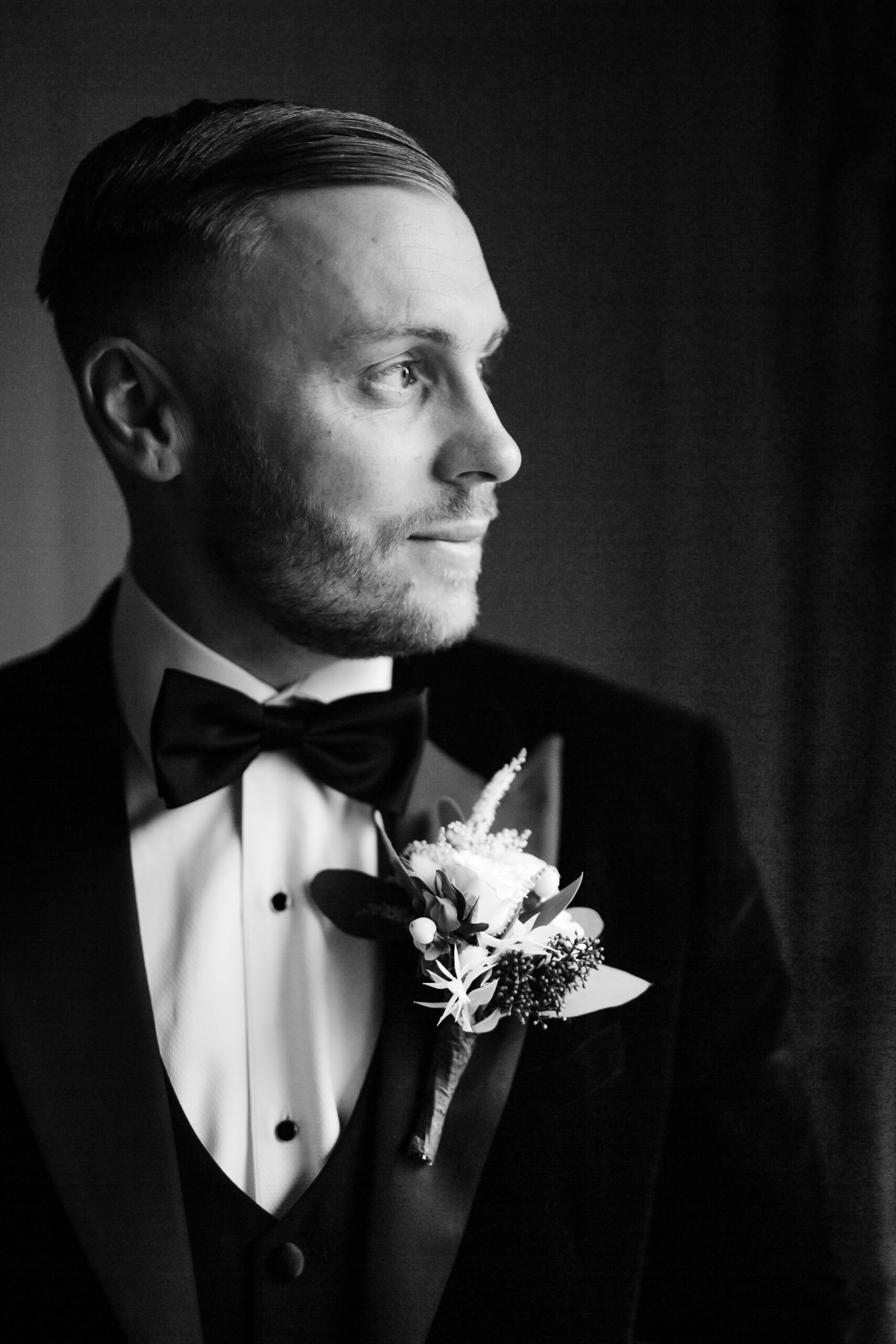 A man in a tuxedo holding a flower