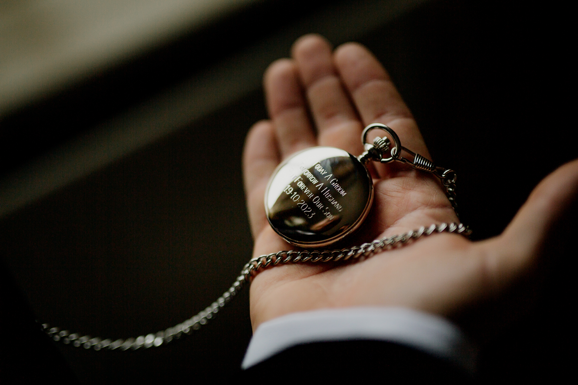 A hand holding a silver watch