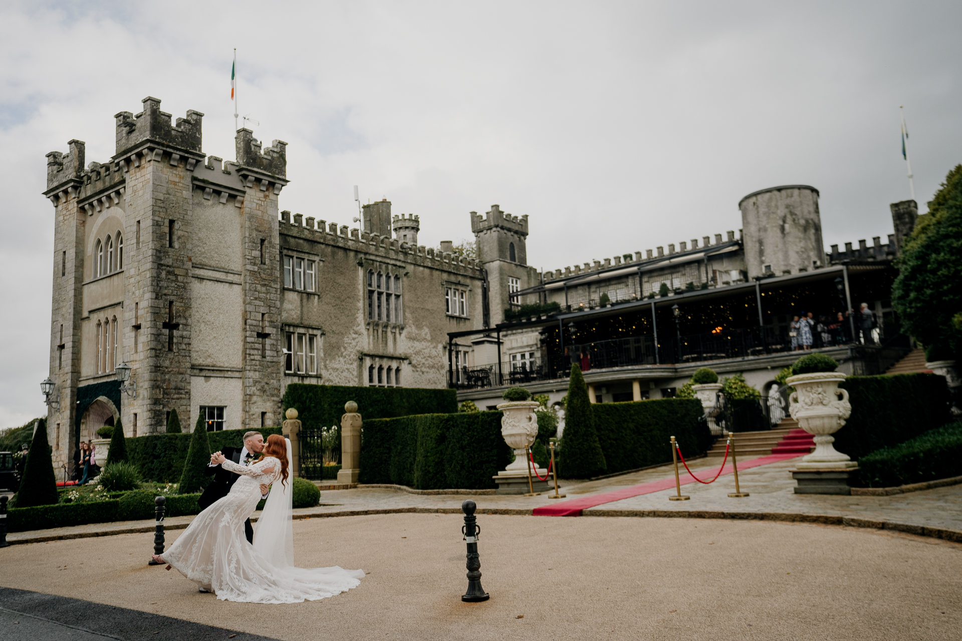 A bride and groom kissing in front of a castle