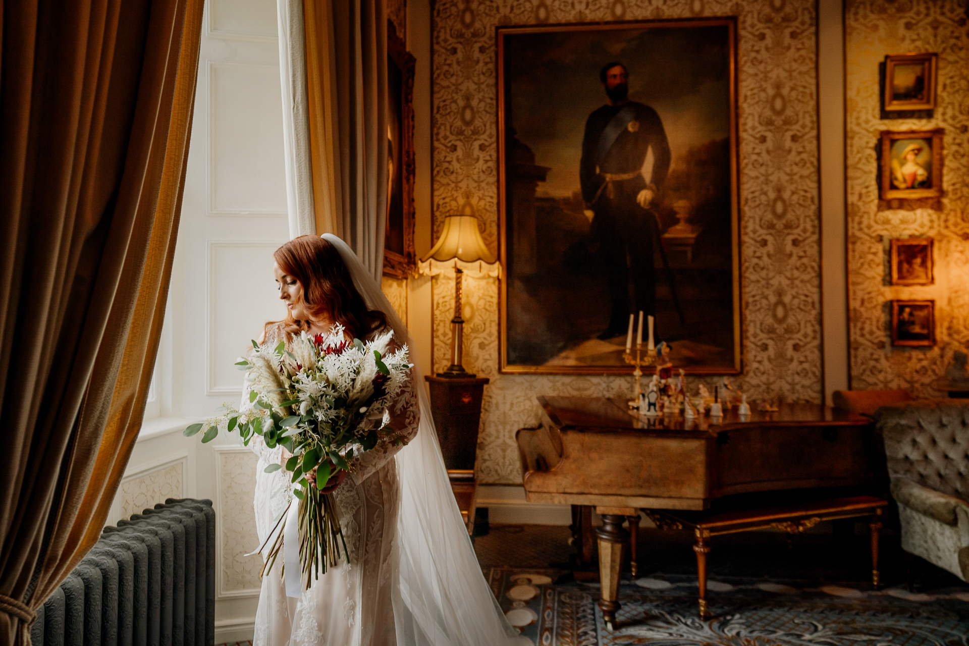 A person in a white dress holding a bouquet of flowers in a room with a painting on the