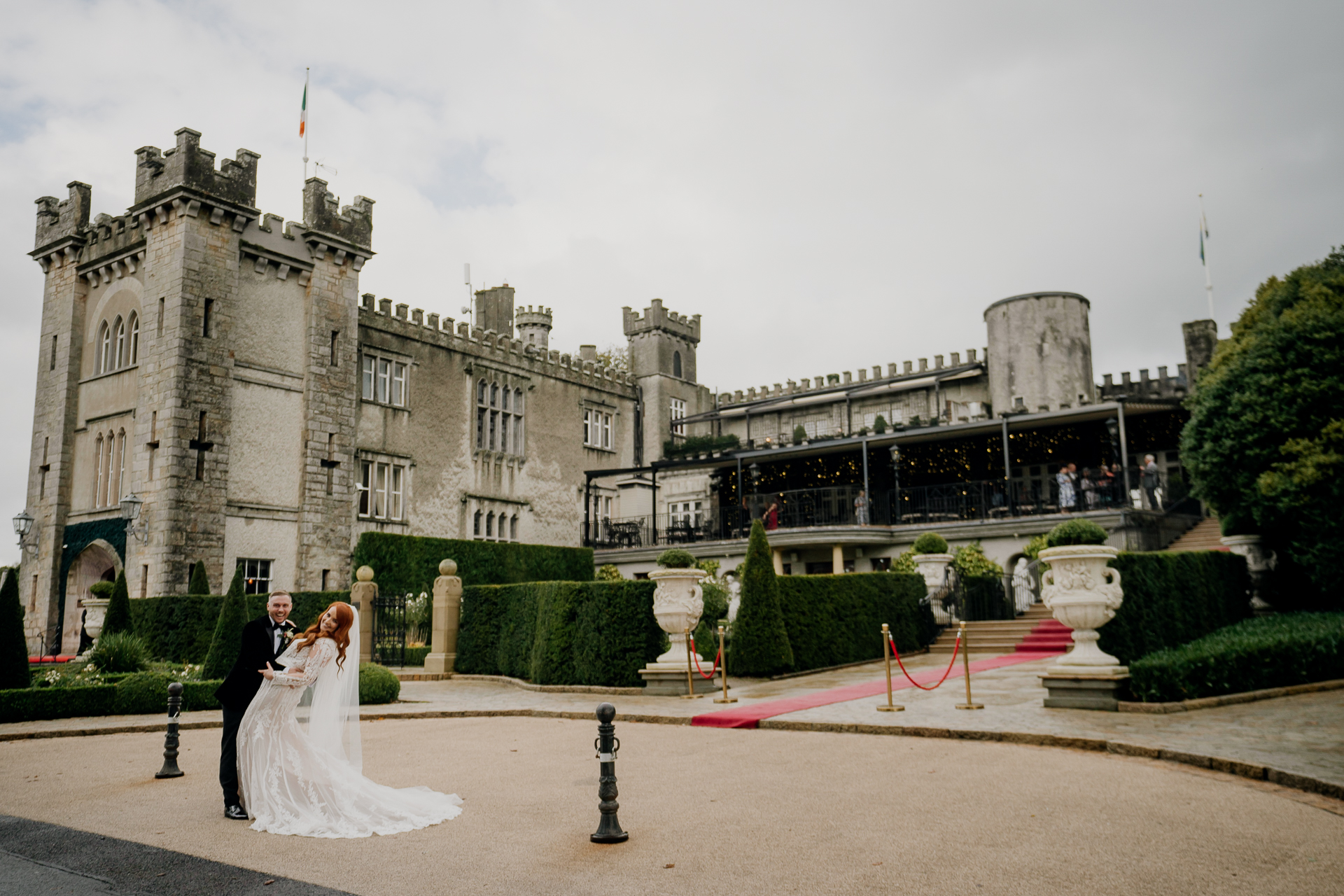 A man and woman in wedding attire in front of a castle