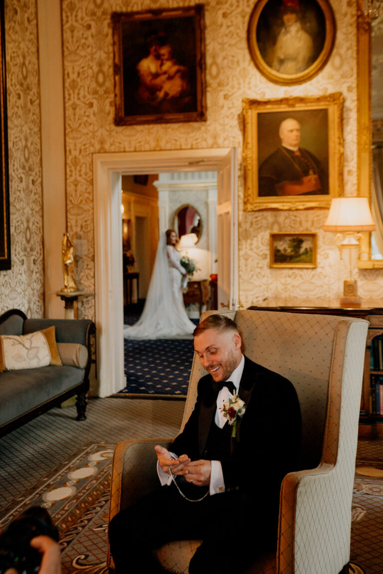 A person in a suit sitting in a chair in front of a mirror