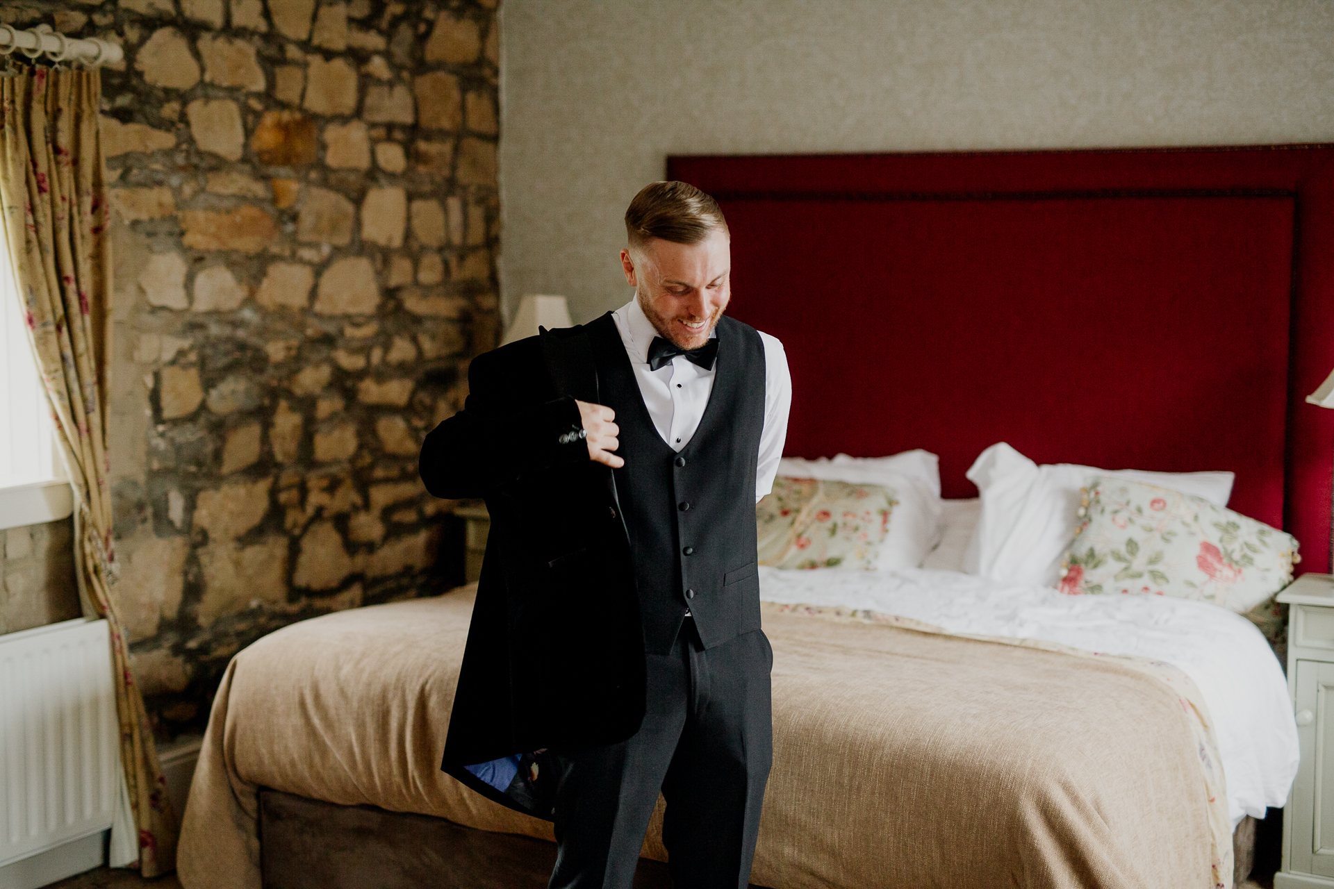 A man in a tuxedo standing next to a bed