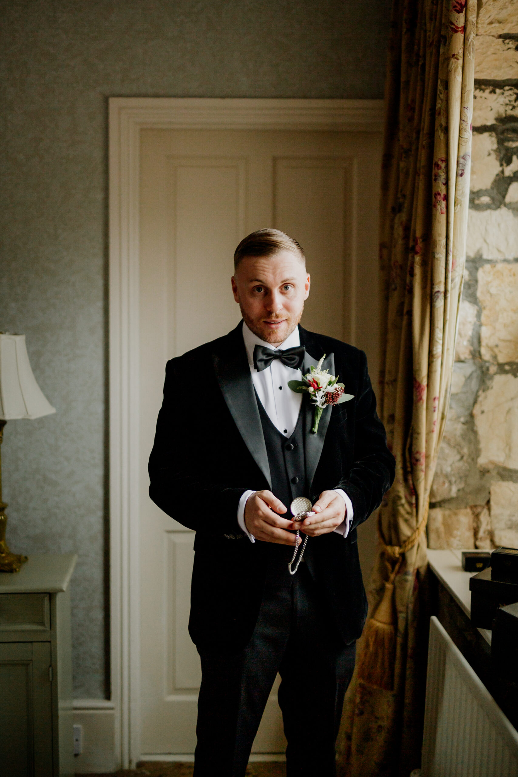 A man in a tuxedo holding a glass of wine