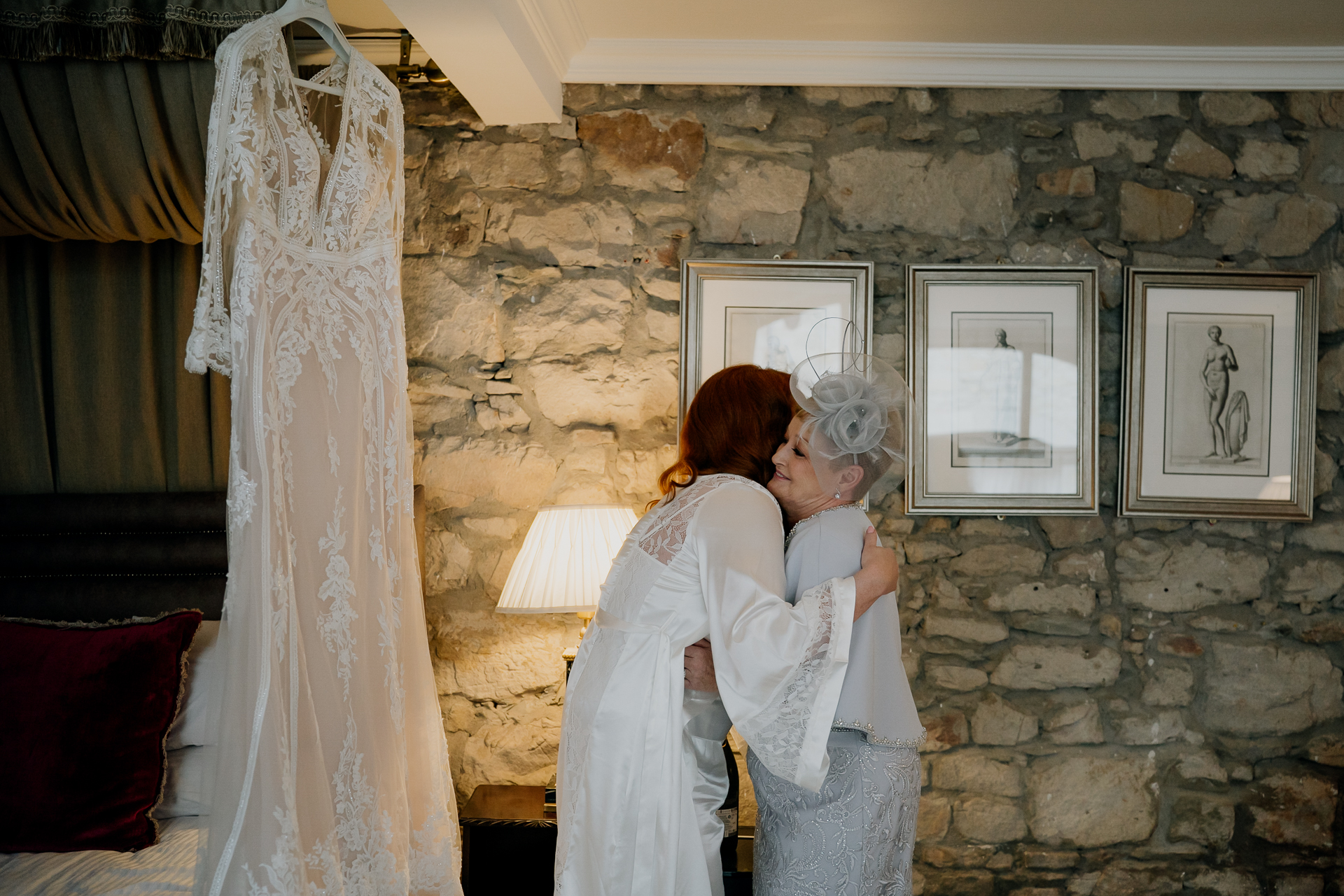 A woman kissing a man in a white robe in a room with a stone wall and pictures