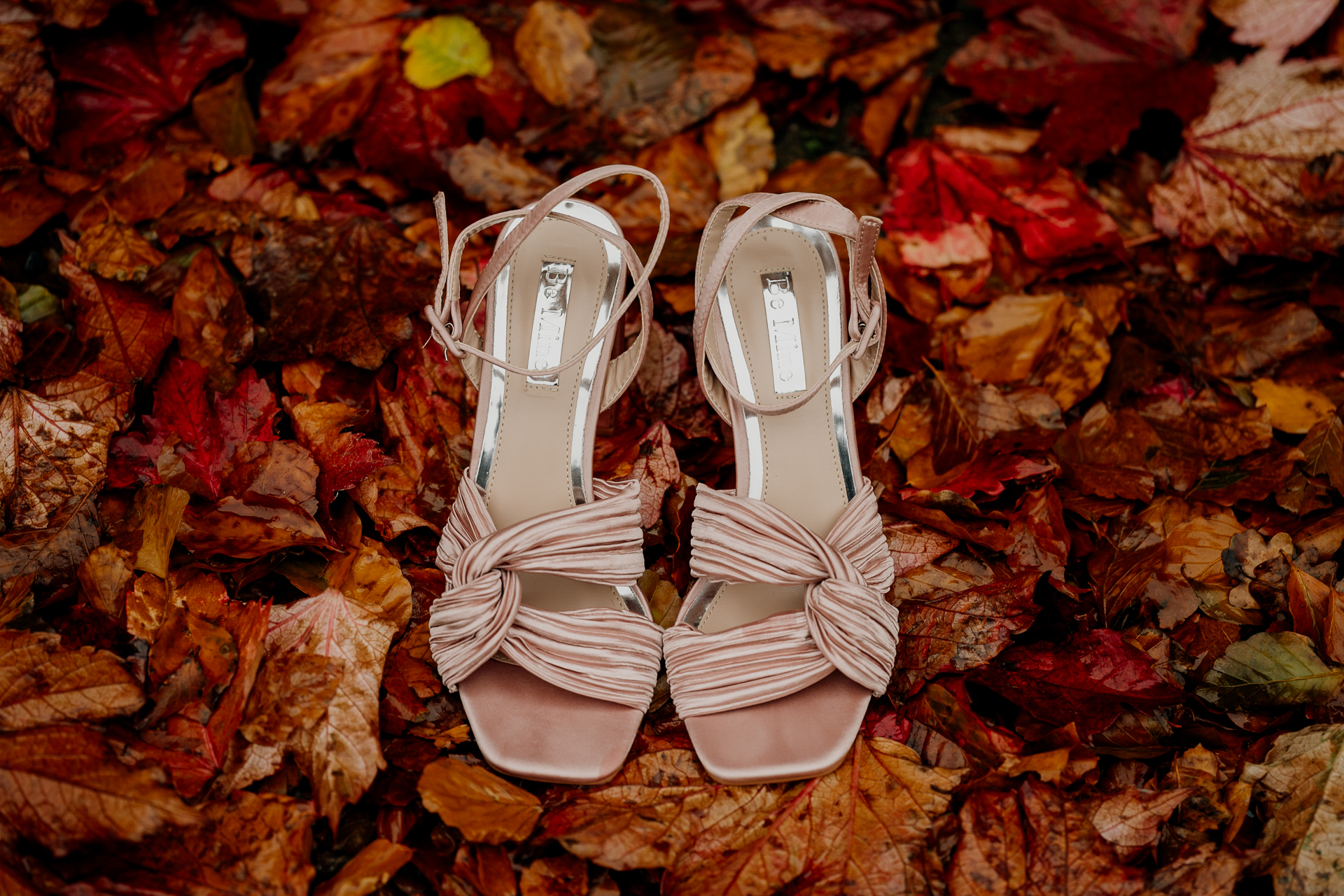 A pair of white shoes on a pile of leaves