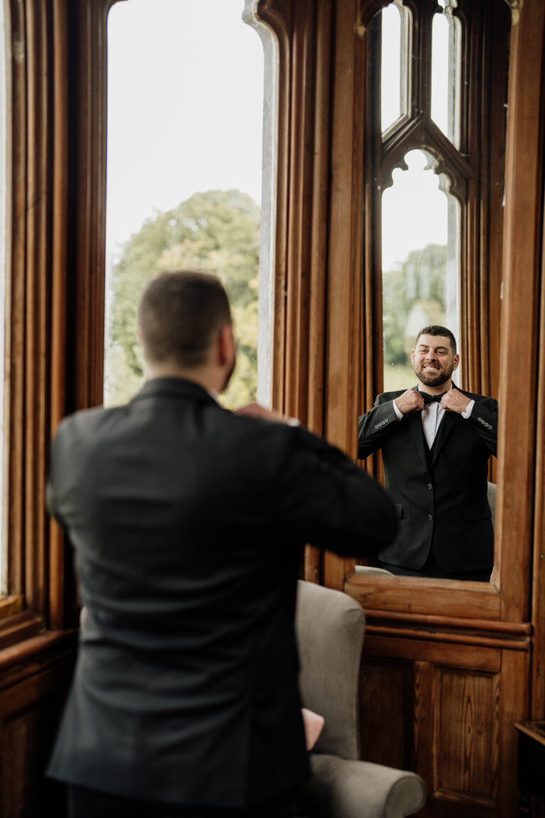 A person in a suit and tie looking at another man in a mirror