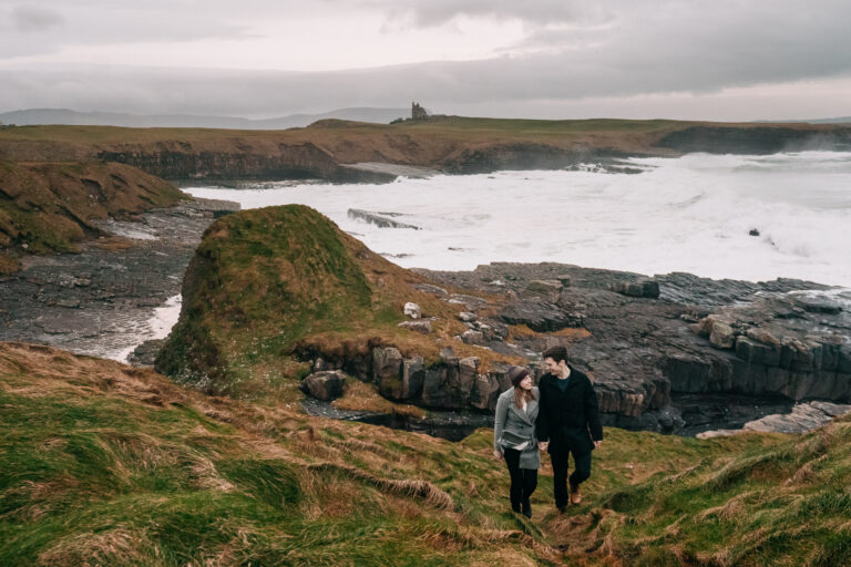 A couple standing on a cliff overlooking a body of water