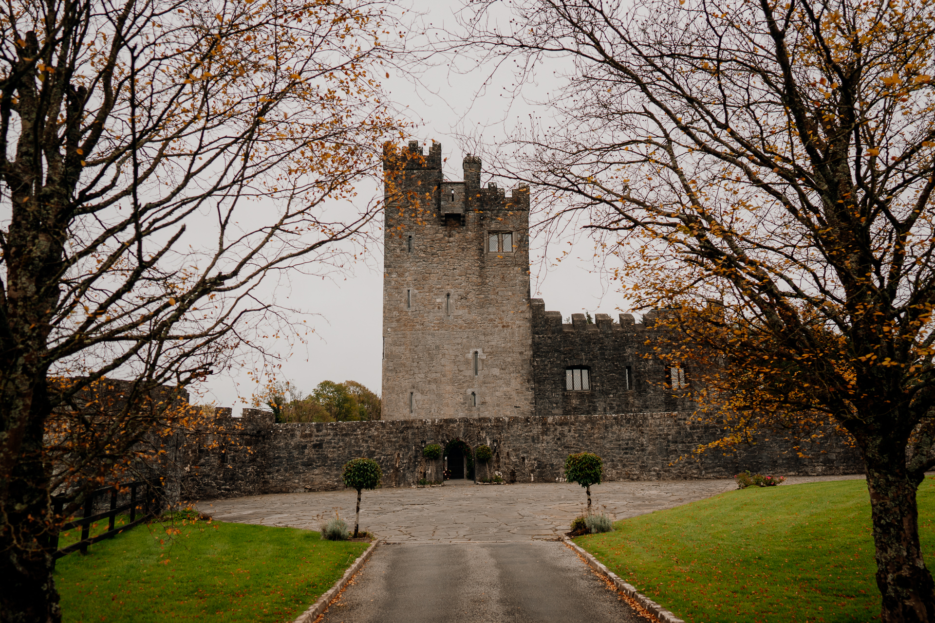 A stone castle with a path and trees on the side