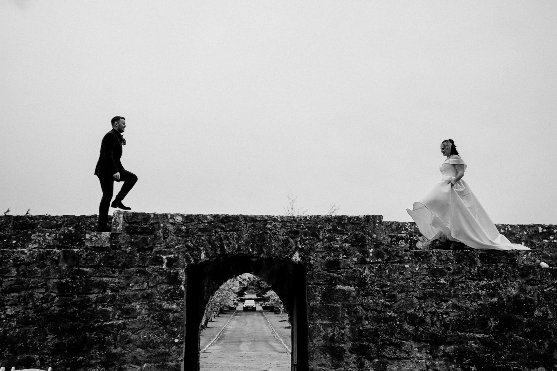 A man and woman jumping on a stone wall