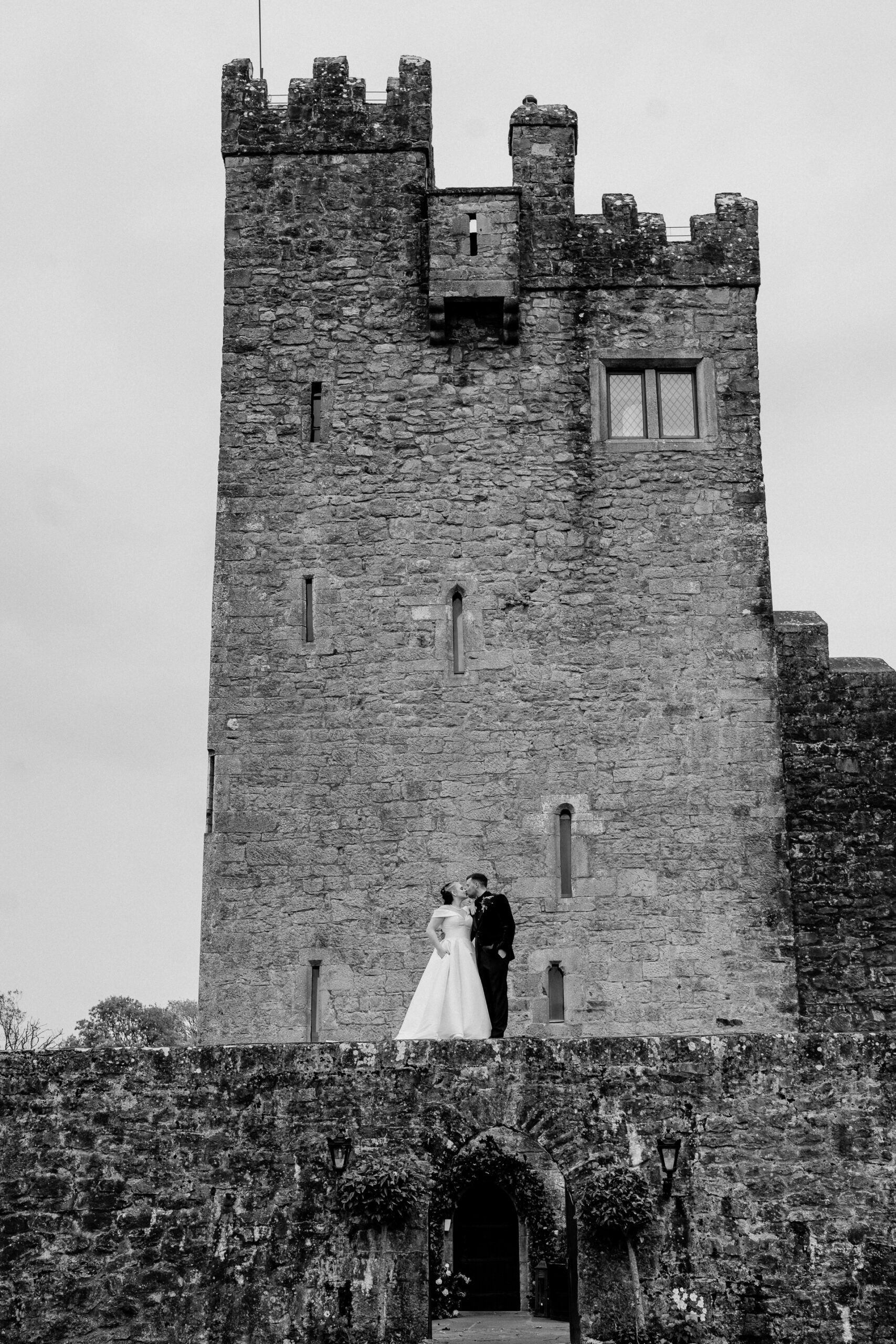 A bride and groom standing in front of a castle