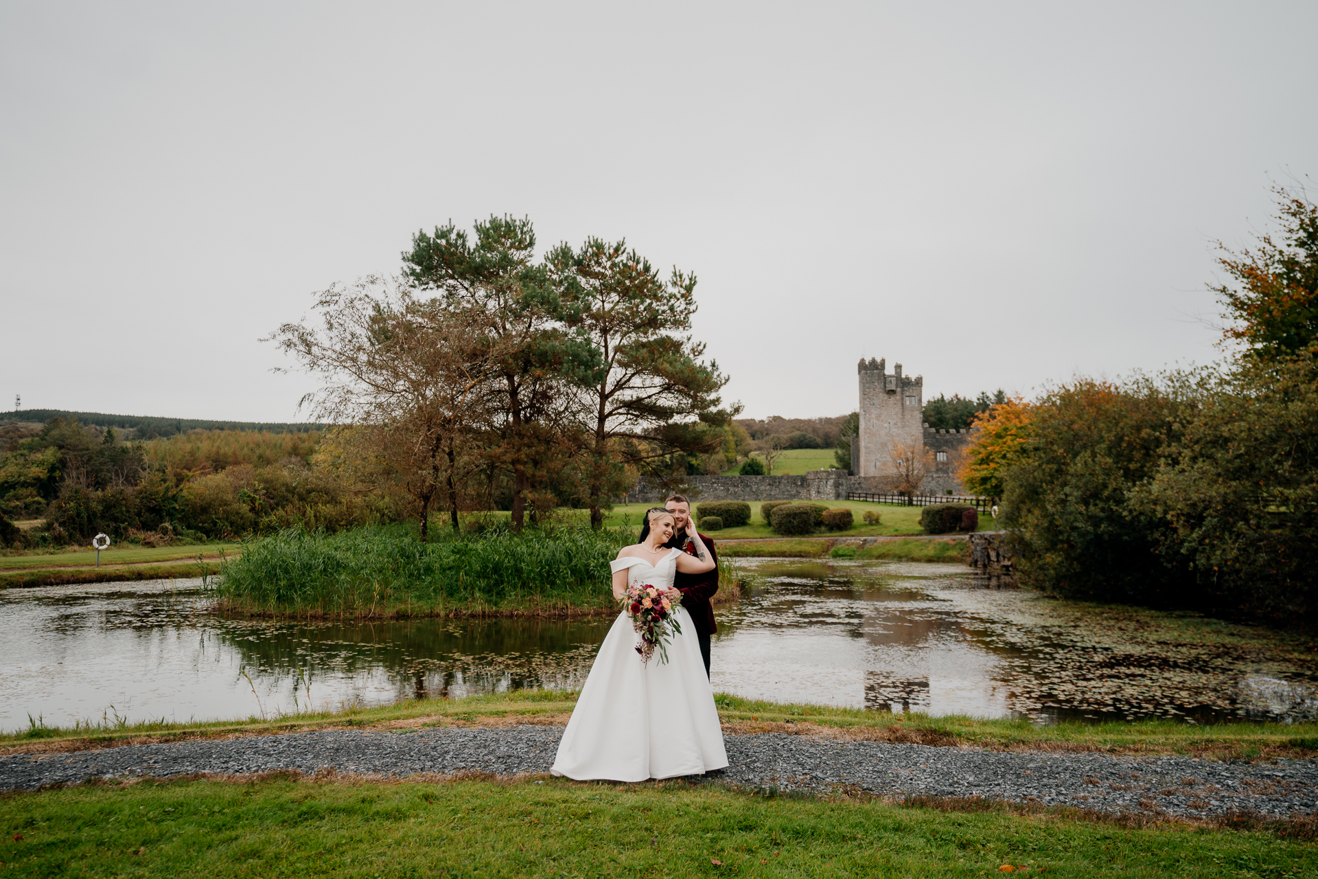 A man and woman in wedding attire kissing in front of a pond