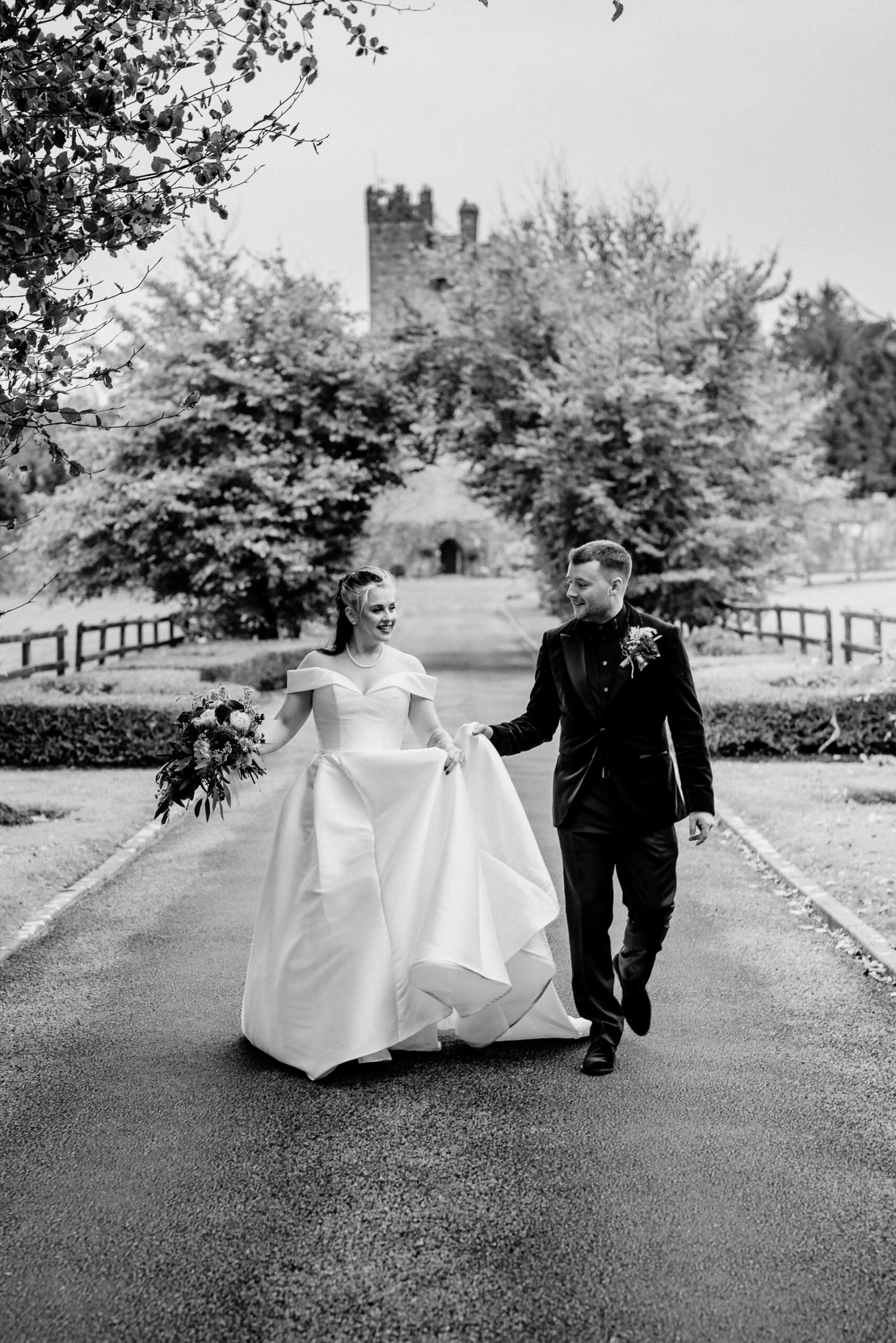 A man and woman walking down a path with a castle in the background