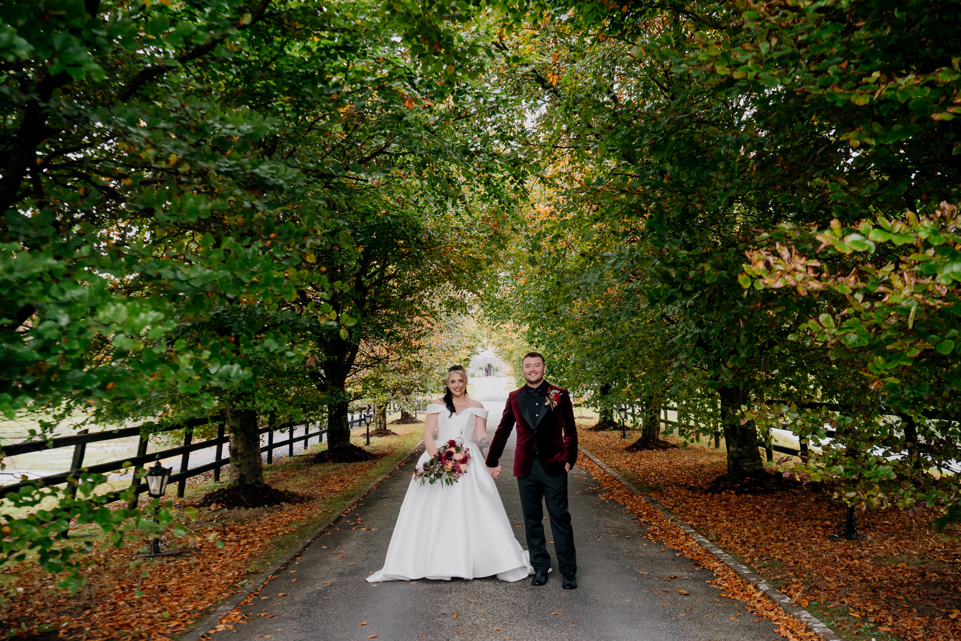 A man and woman walking down a path with trees on either side