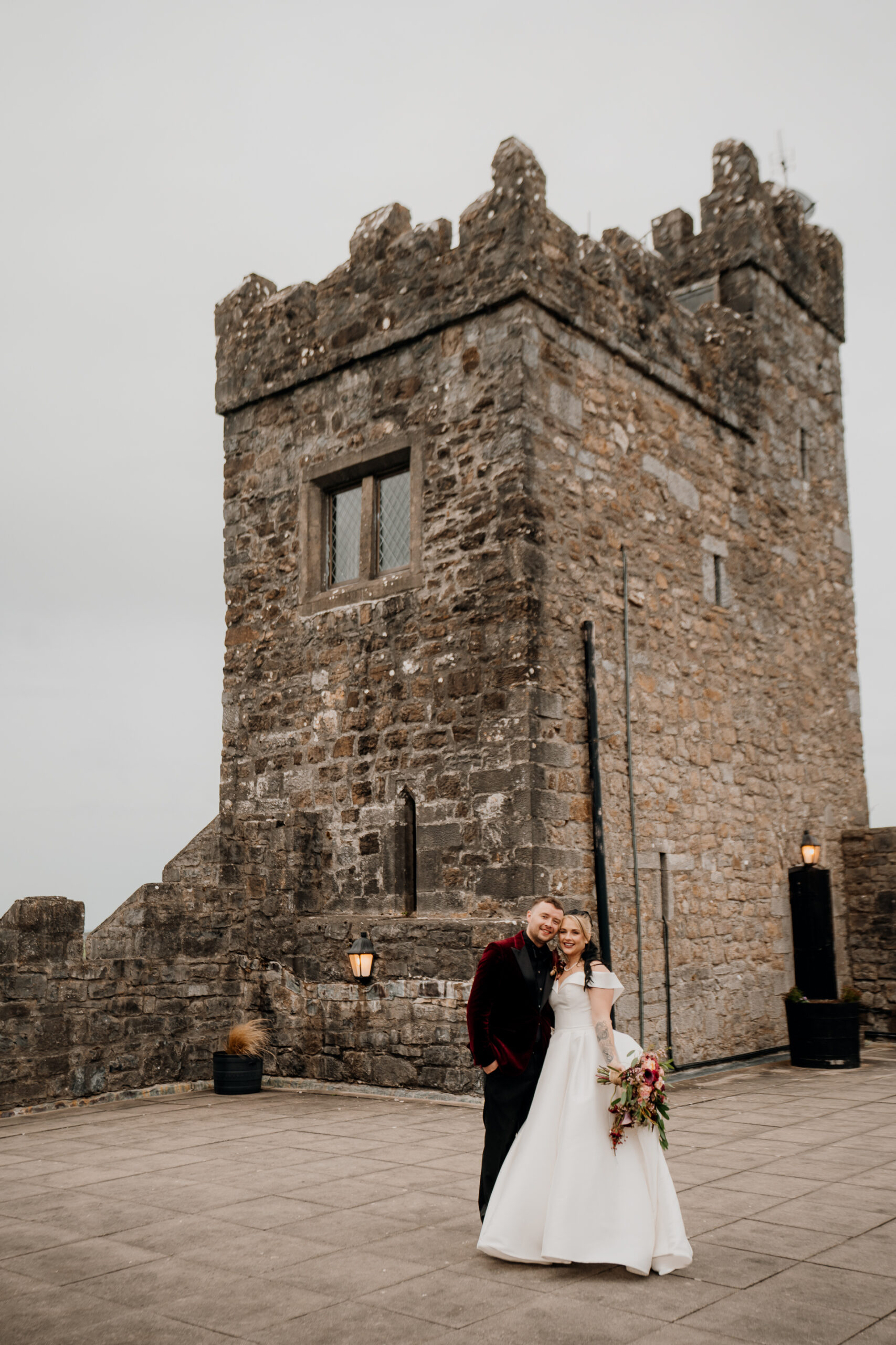 A man and woman kissing in front of a stone castle