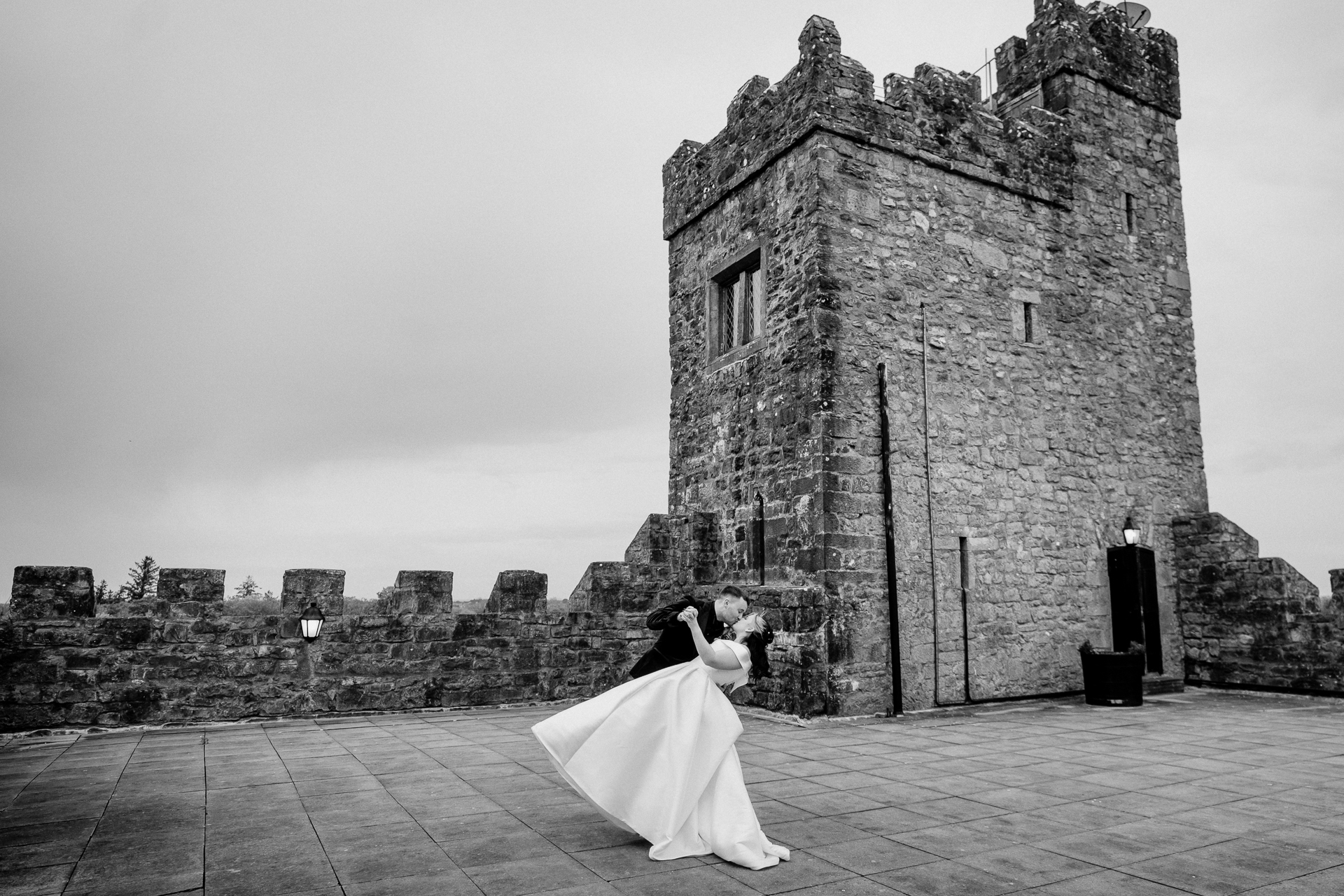 A bride and groom kissing in front of a castle