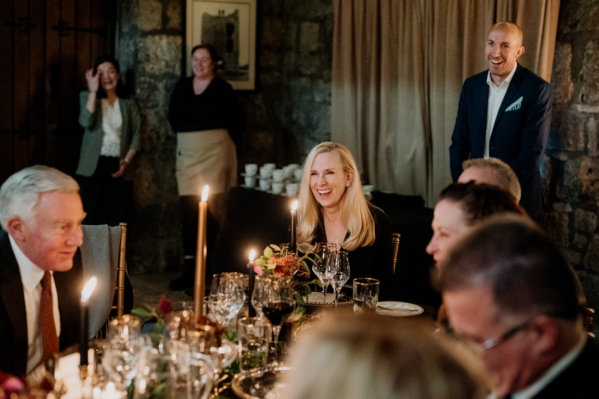 A group of people around a table with candles and glasses