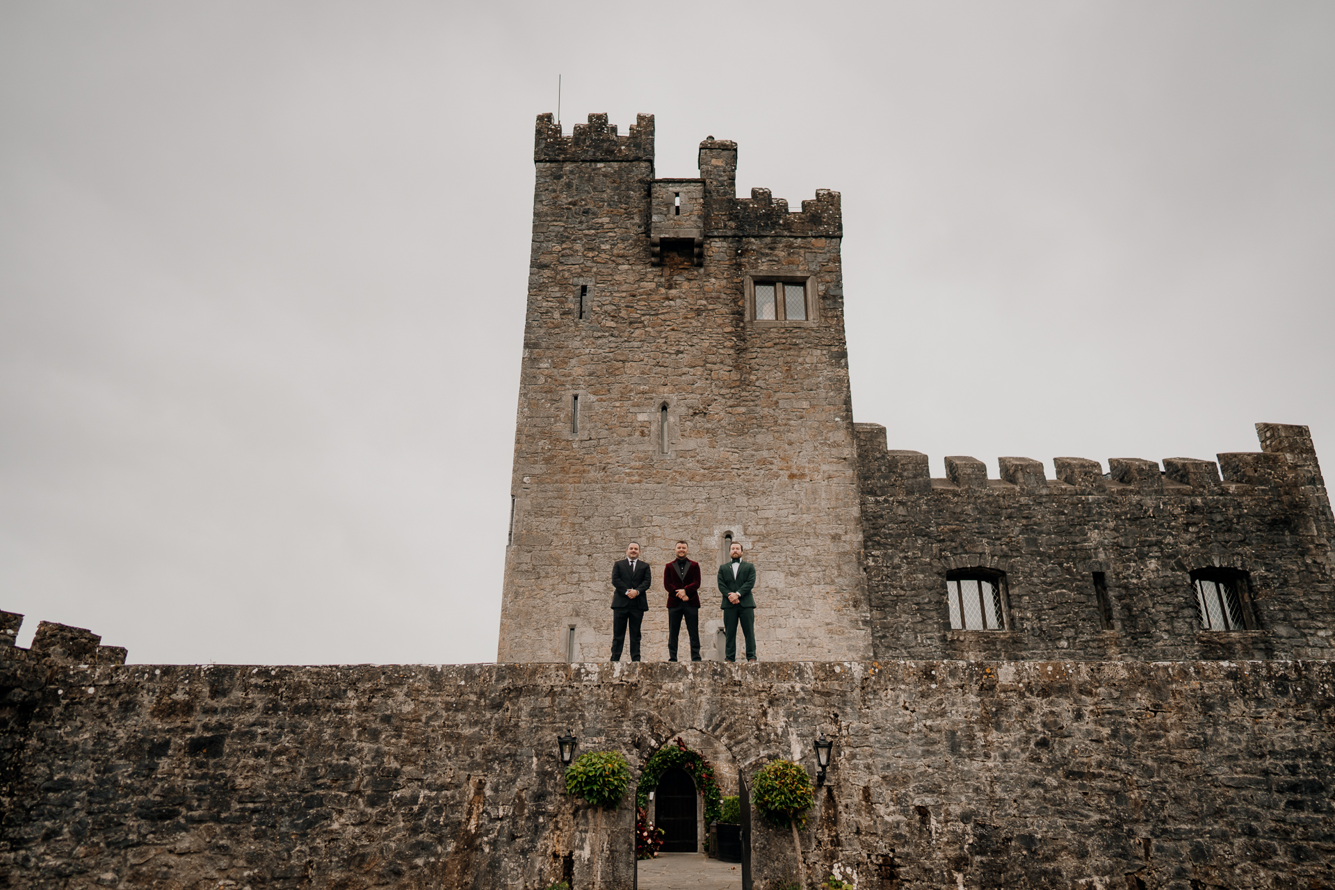 A group of people standing on a stone wall in front of a castle