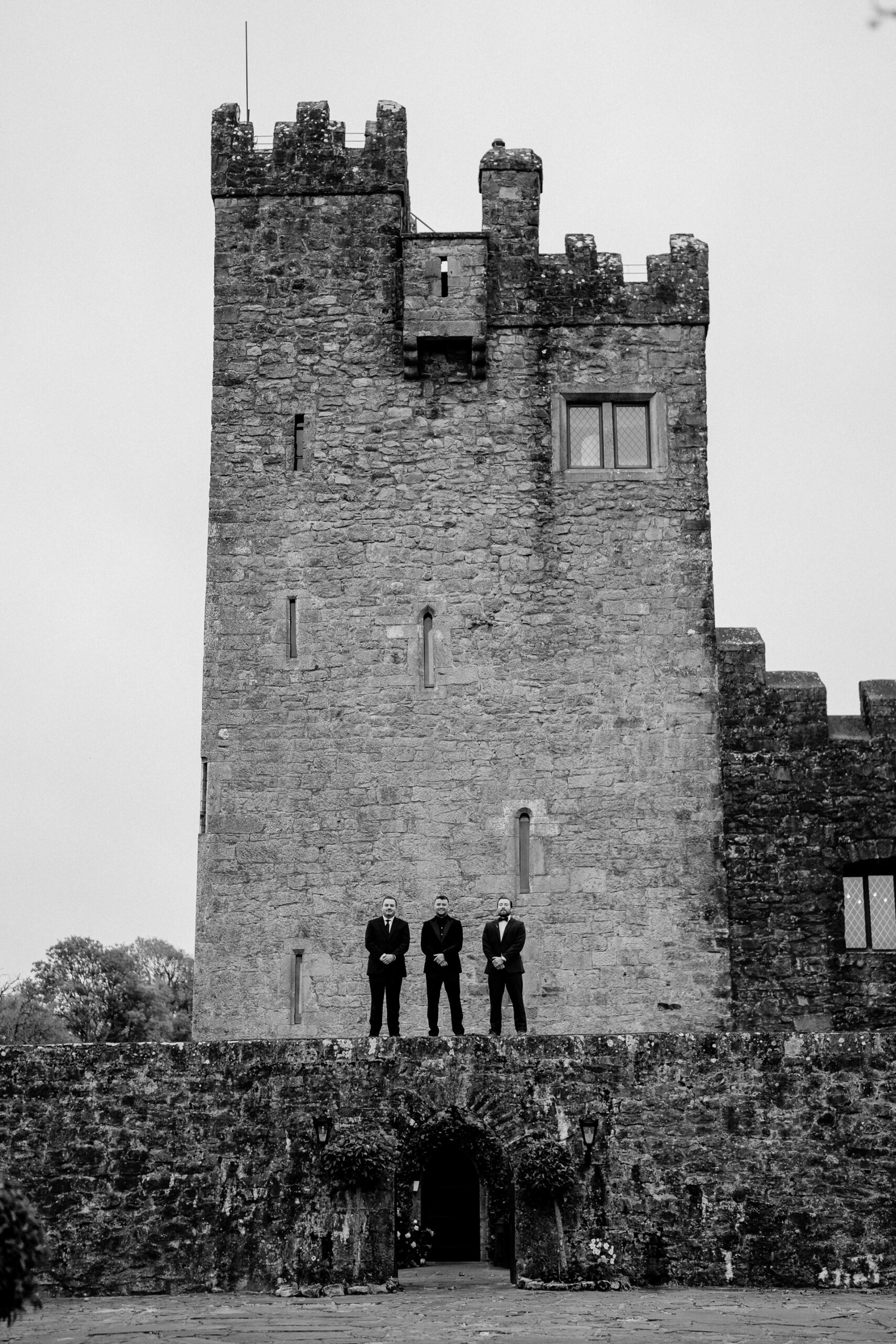 A group of men standing on a stone tower with Rochester Castle in the background