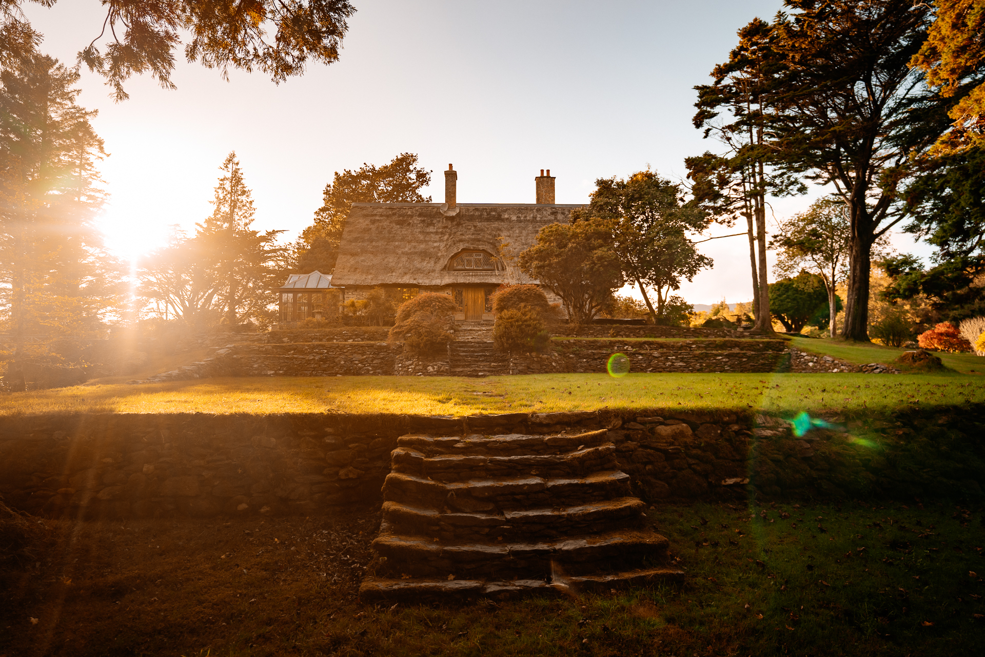 A stone staircase leading up to a house with trees and grass