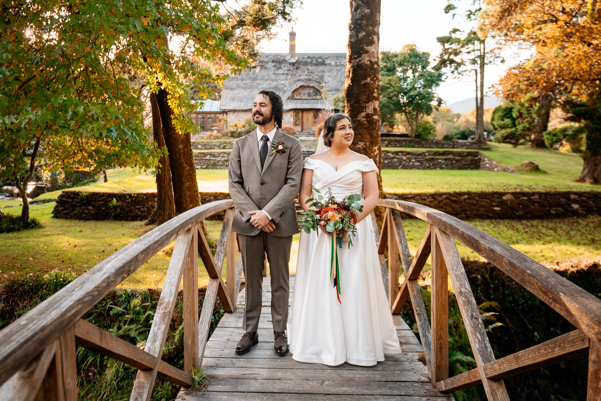 A man and woman in wedding attire standing on a bridge