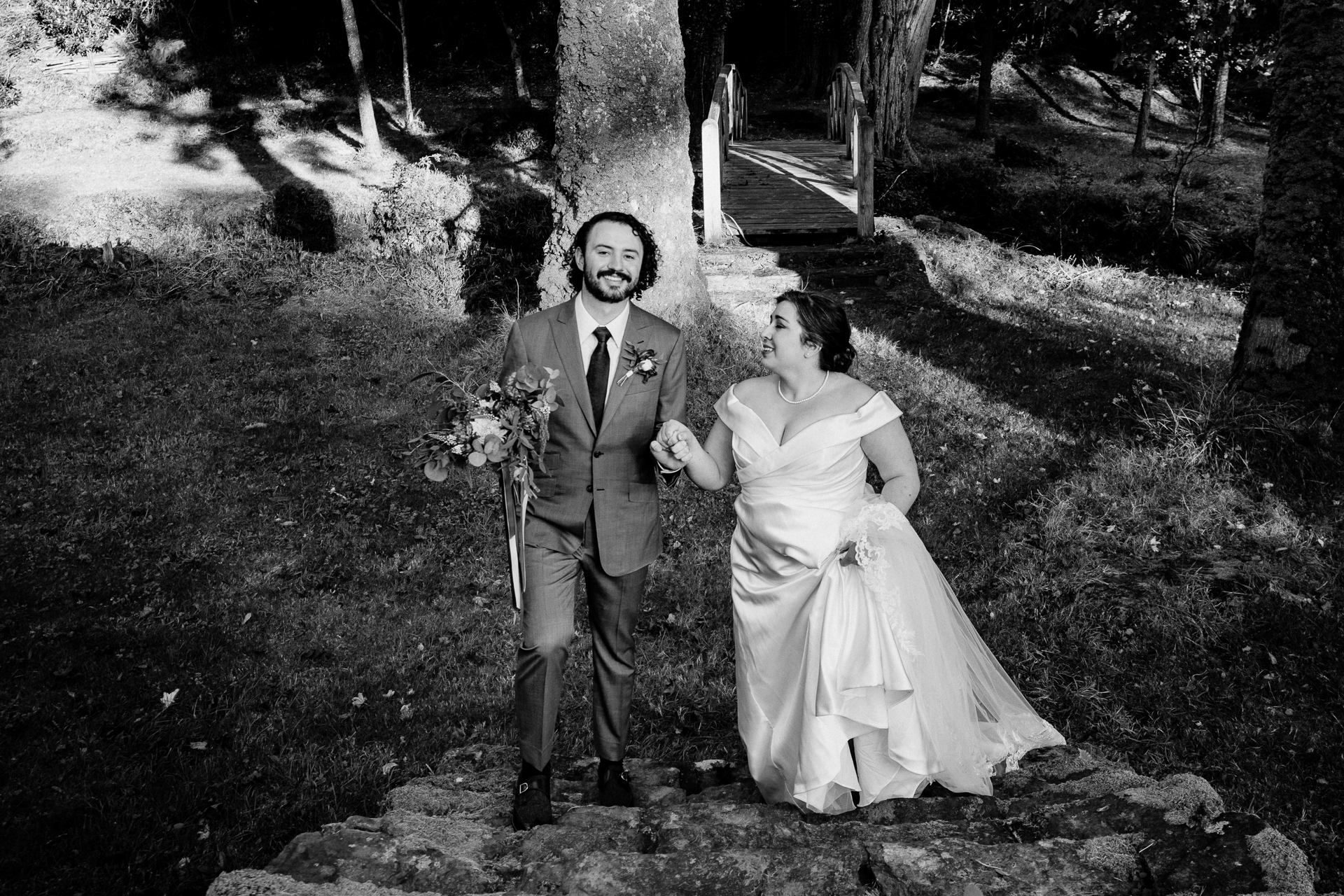 A bride and groom walking down a path with a person in a suit