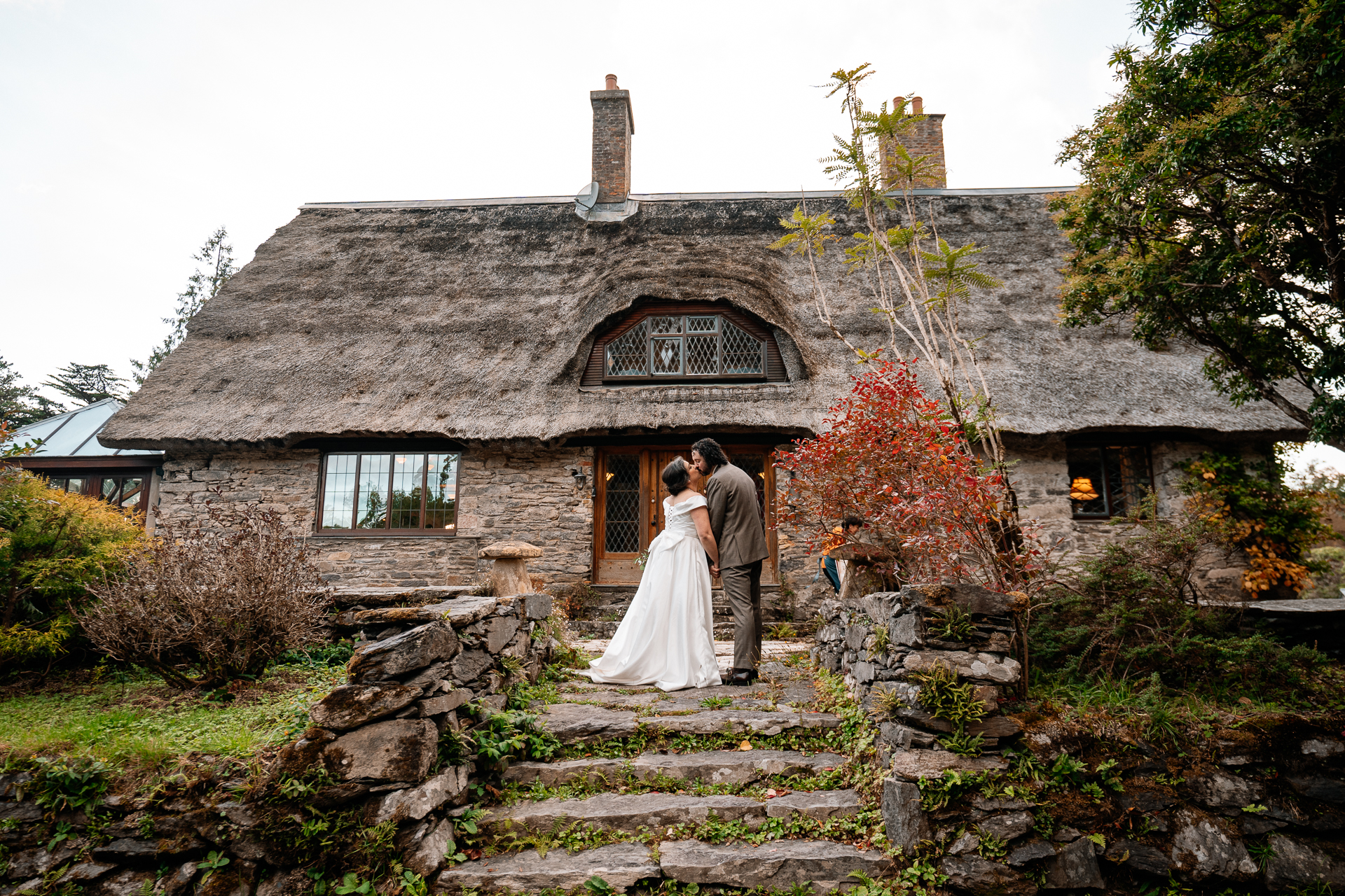 A bride and groom kissing on steps outside of a house