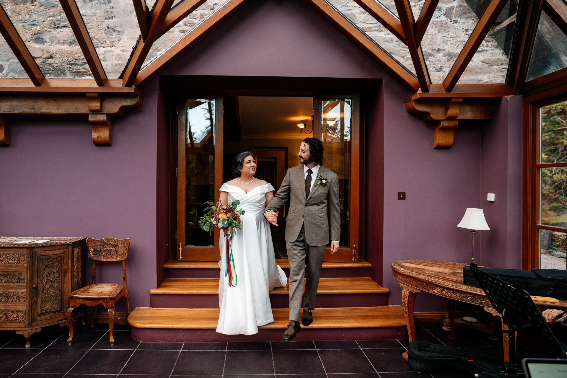 A man and woman walking down a hall with a table and chairs