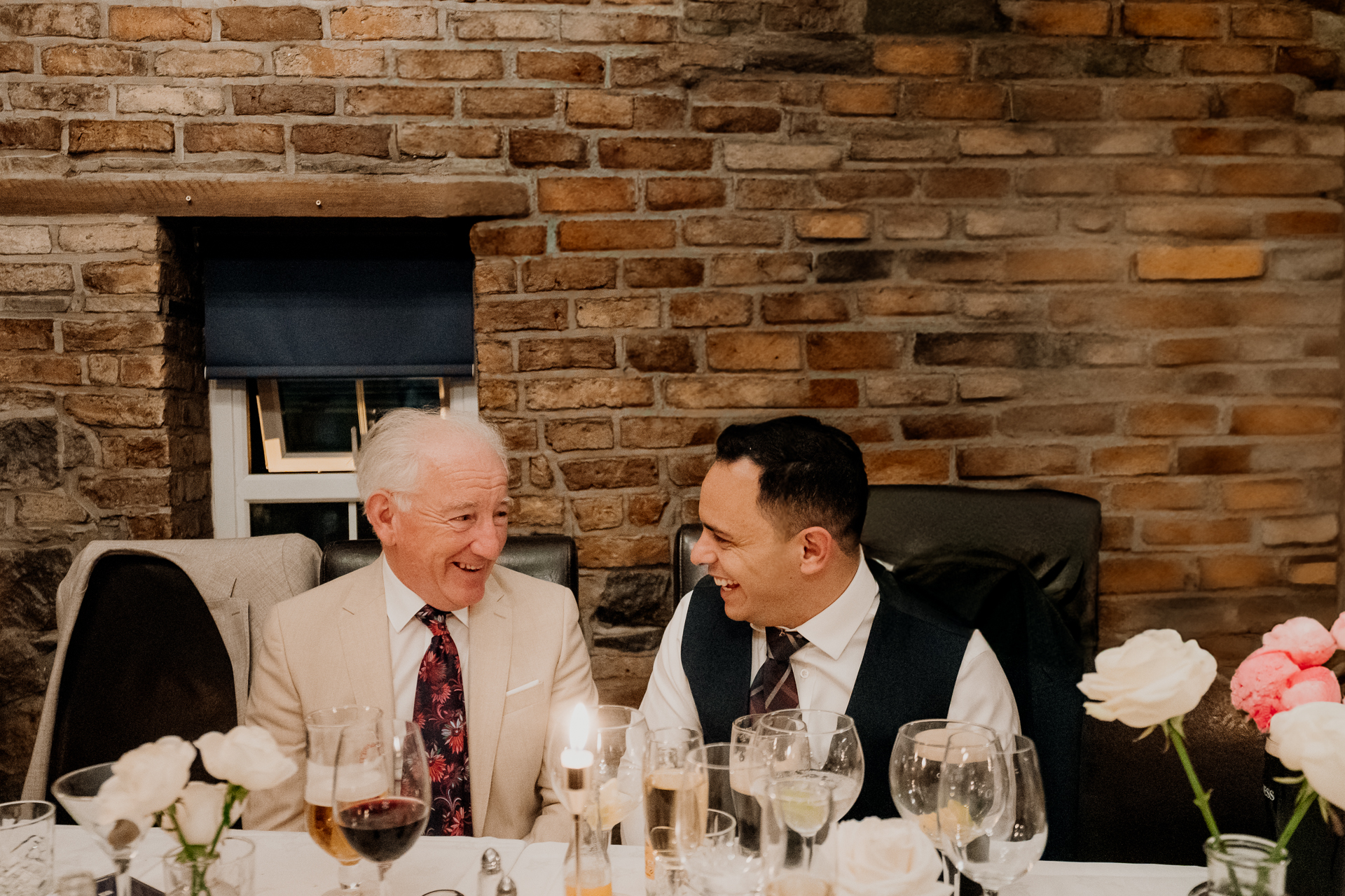 A couple of men sitting at a table with wine glasses