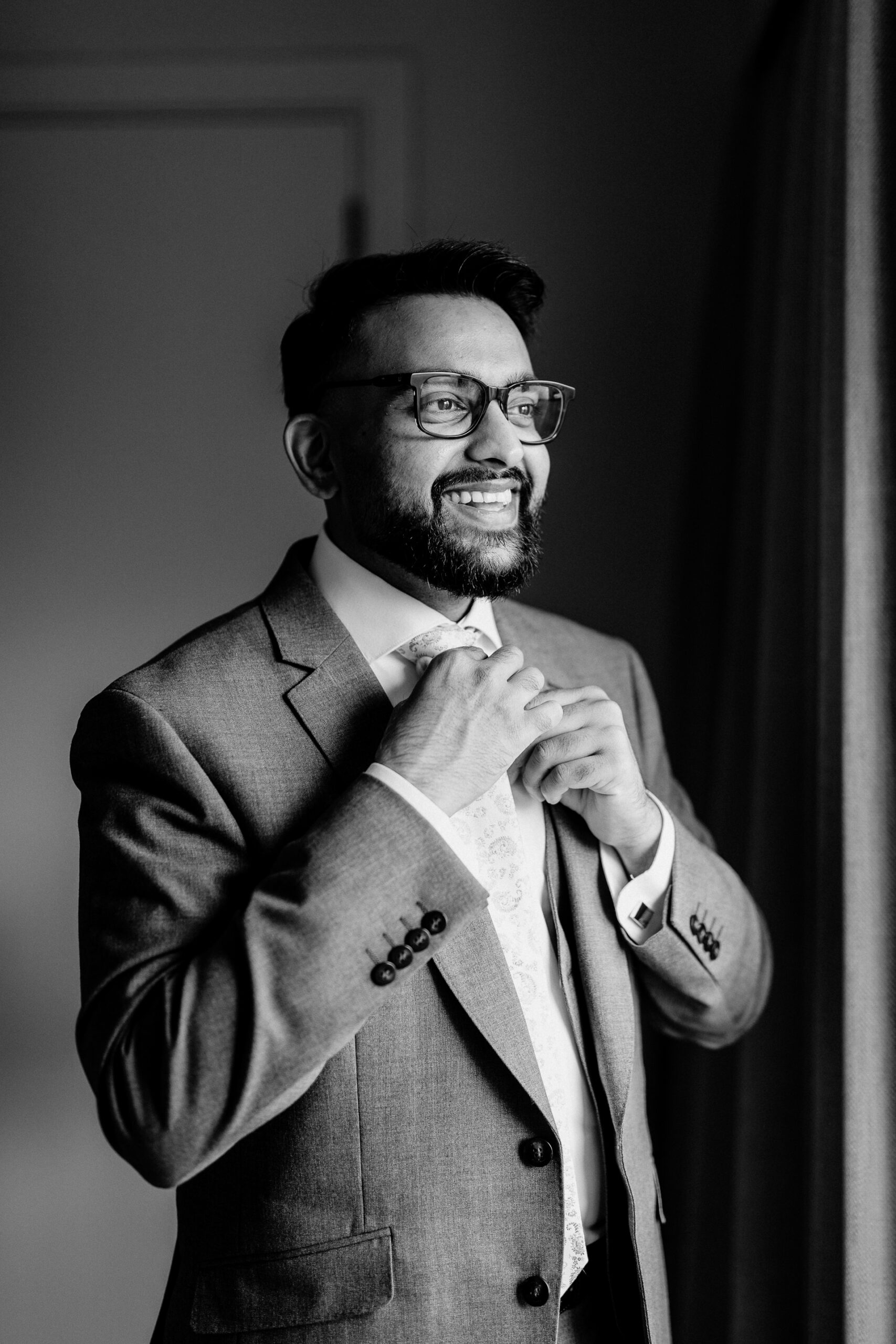 A man in a suit adjusting his tie