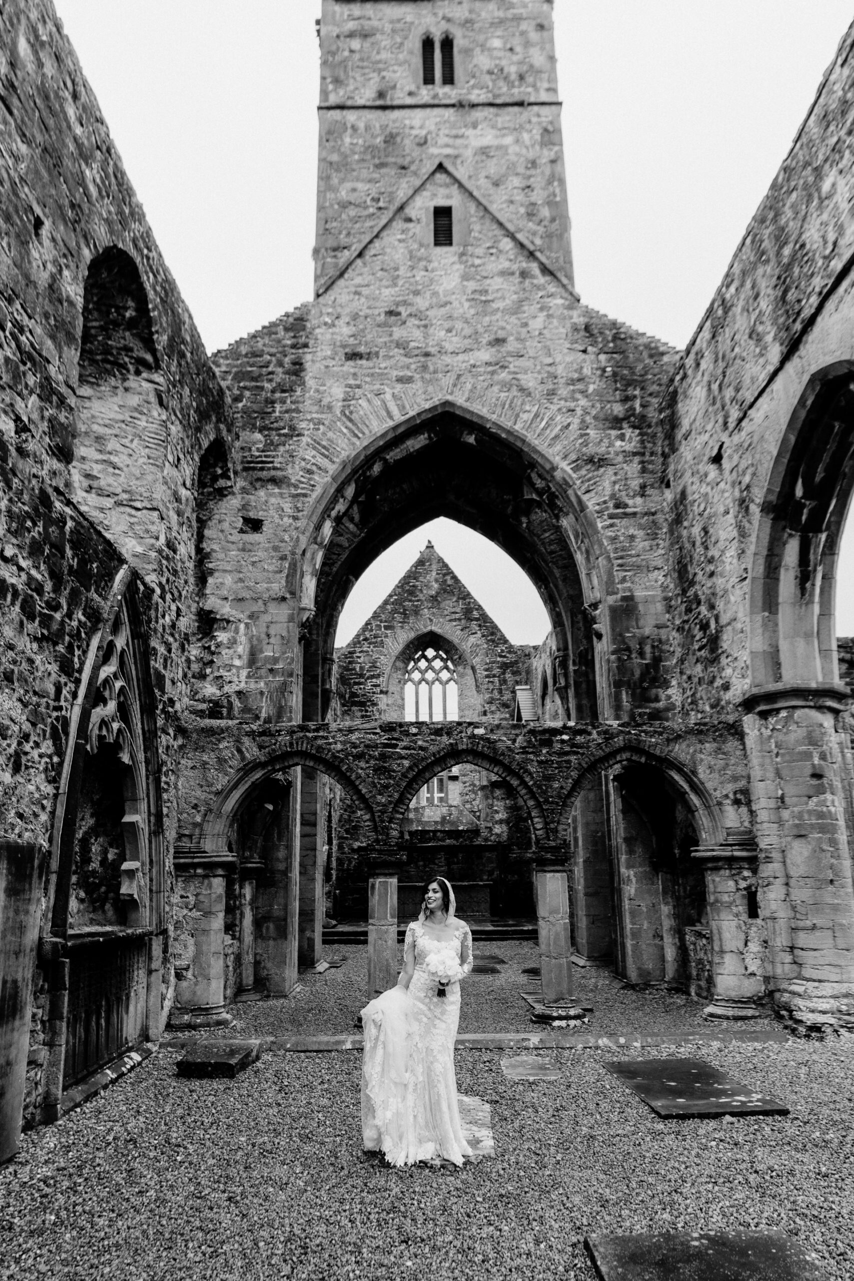 A person in a white dress standing in front of a stone building