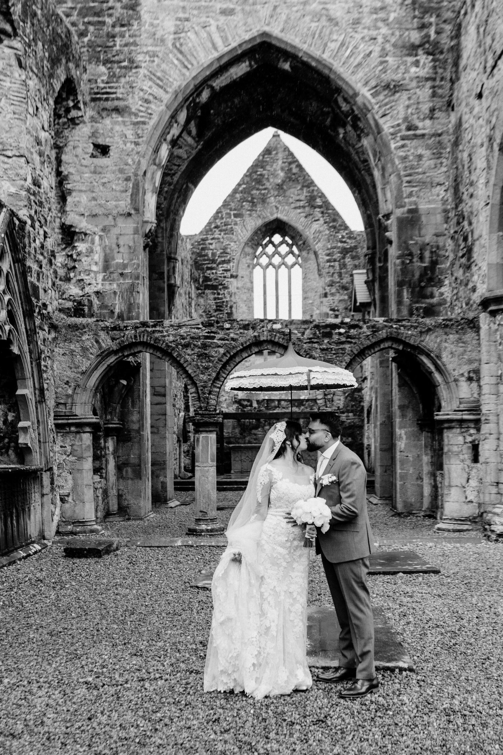 A bride and groom kissing in a stone building