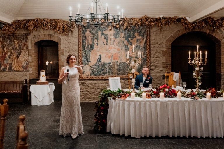 A woman in a dress standing next to a table with a man sitting at it