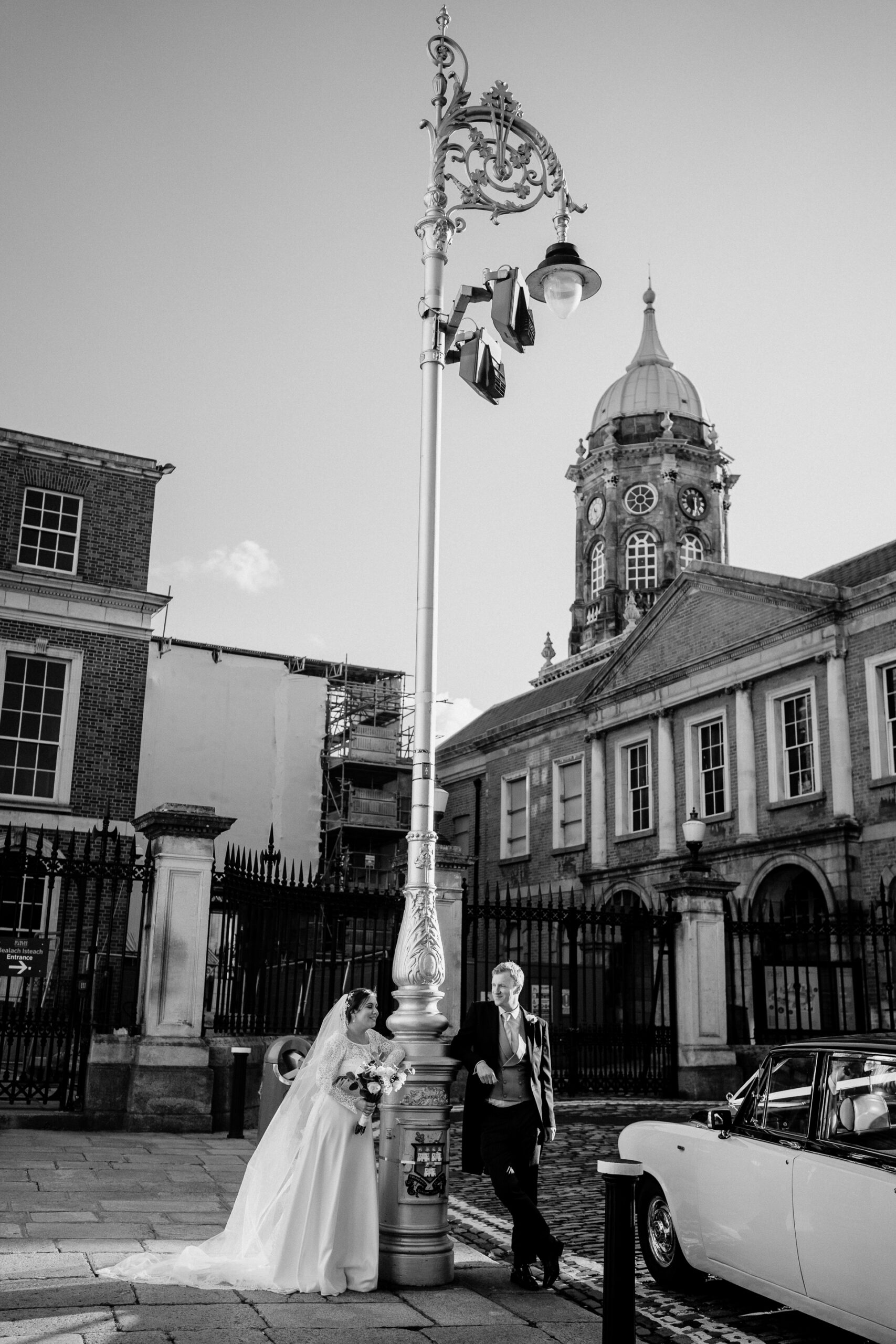 A bride and groom standing next to a large pole