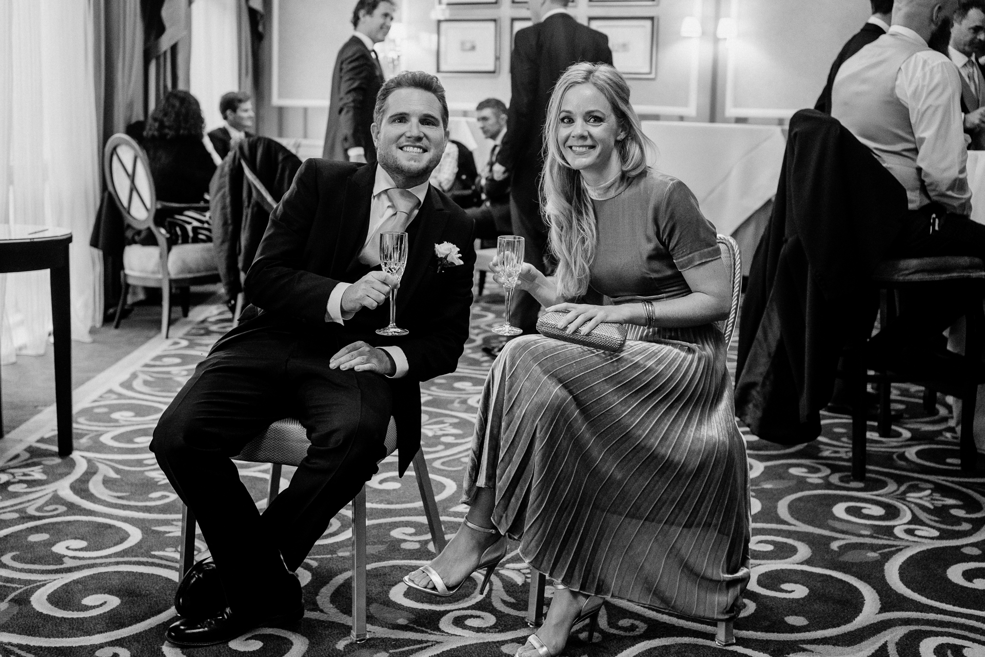 A man and woman sitting on a chair and holding wine glasses