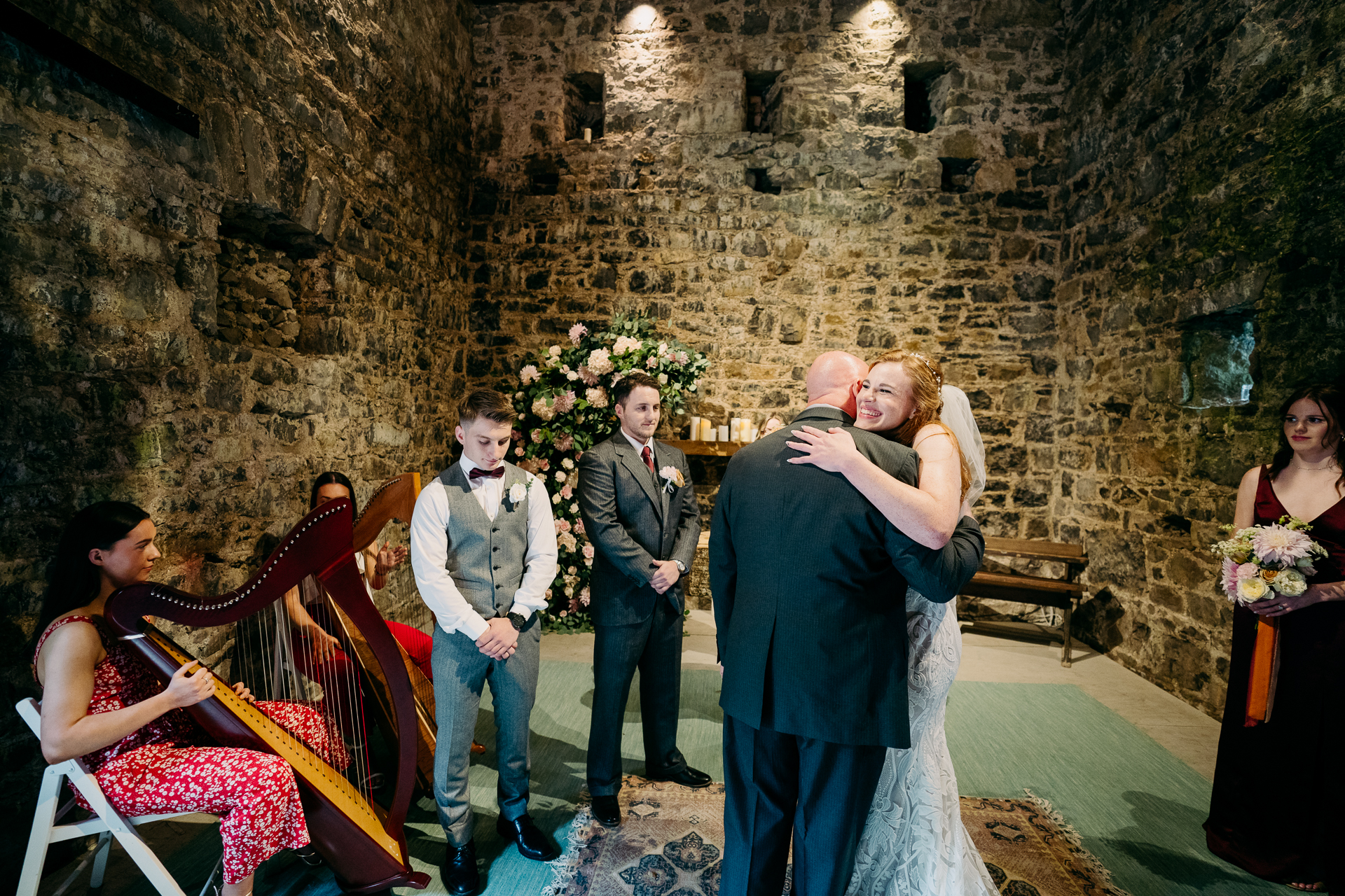 A group of people standing in a room with a stone wall